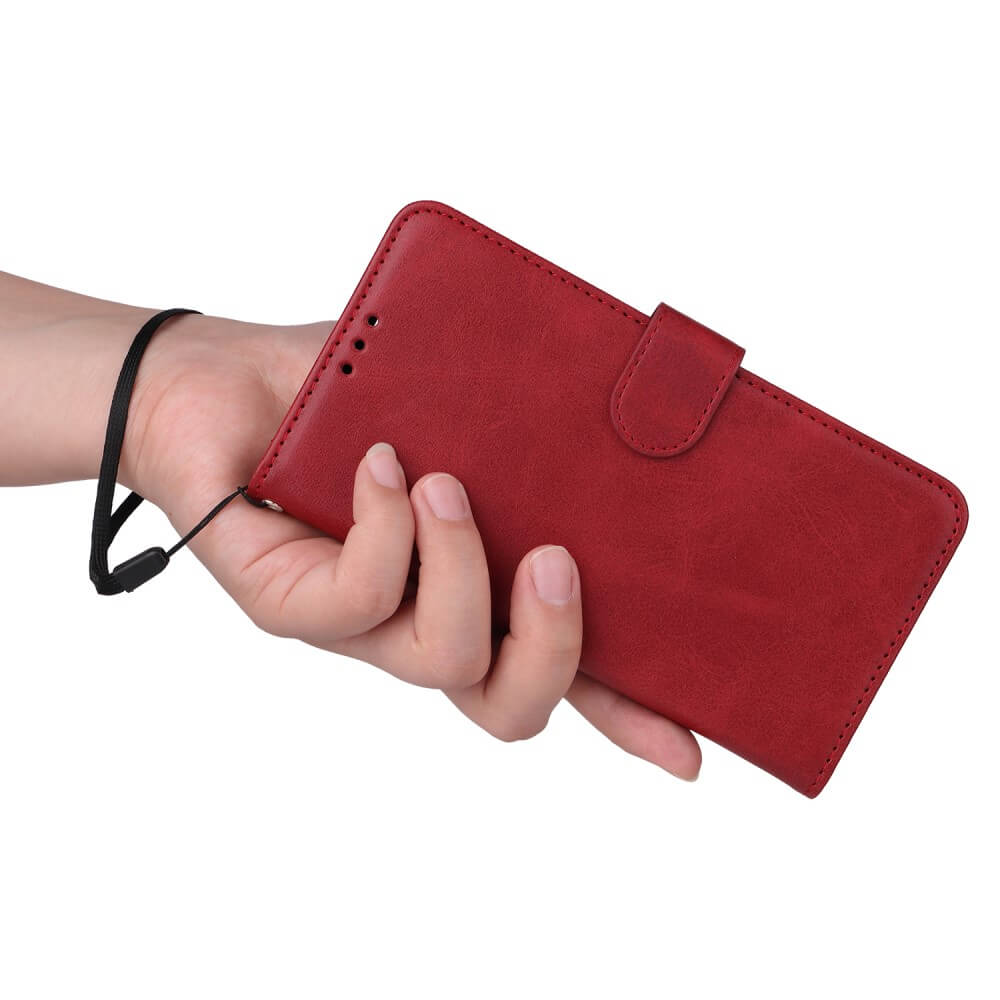 Una mano tiene una custodia per telefono in pelle rossa con cinturino nero su sfondo bianco.