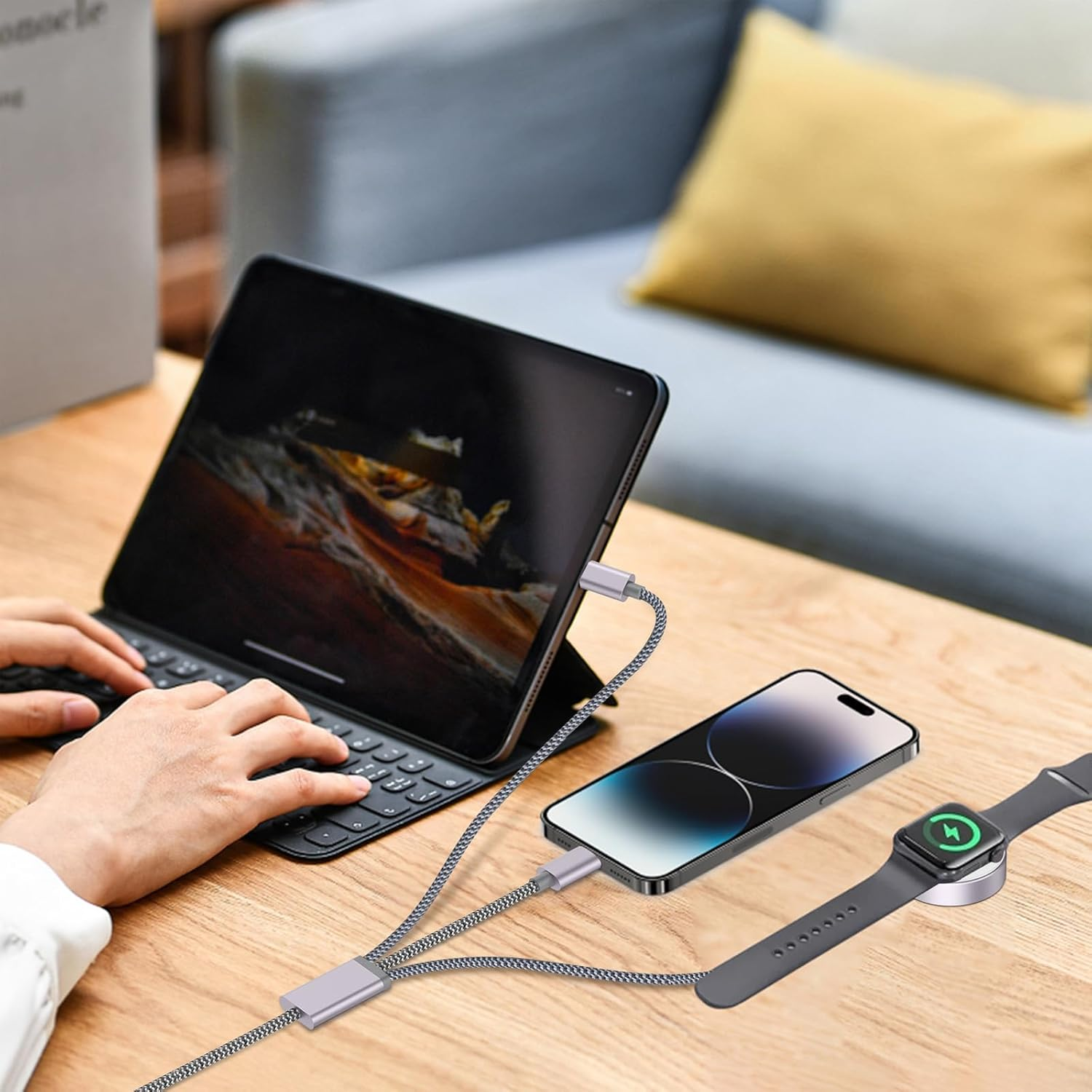 Hände tippen auf Tablet-Tastatur; Handy und Uhr laden auf Tisch.