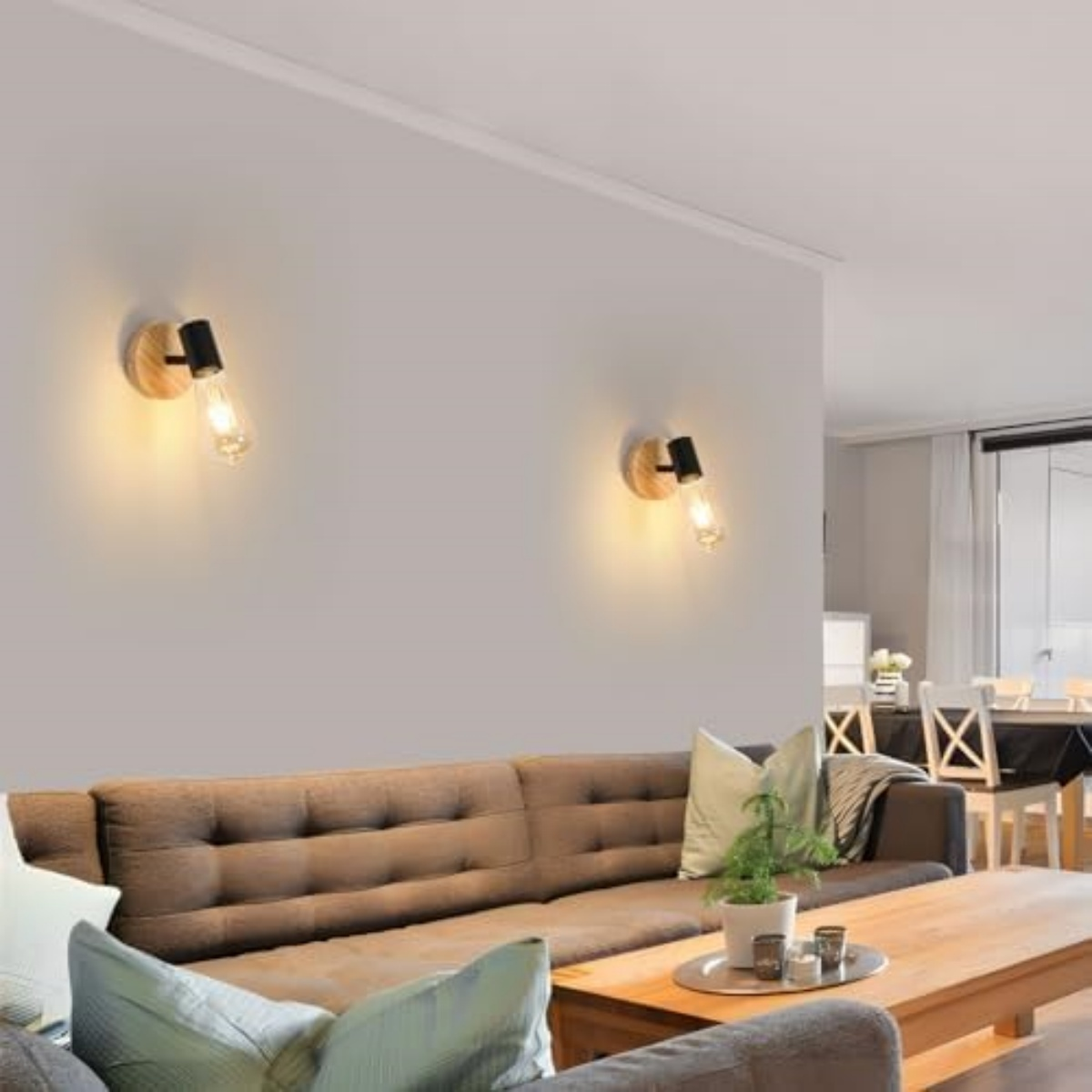 Zwei Wandleuchten beleuchten eine Wand über einem braunen Sofa mit Kissen.