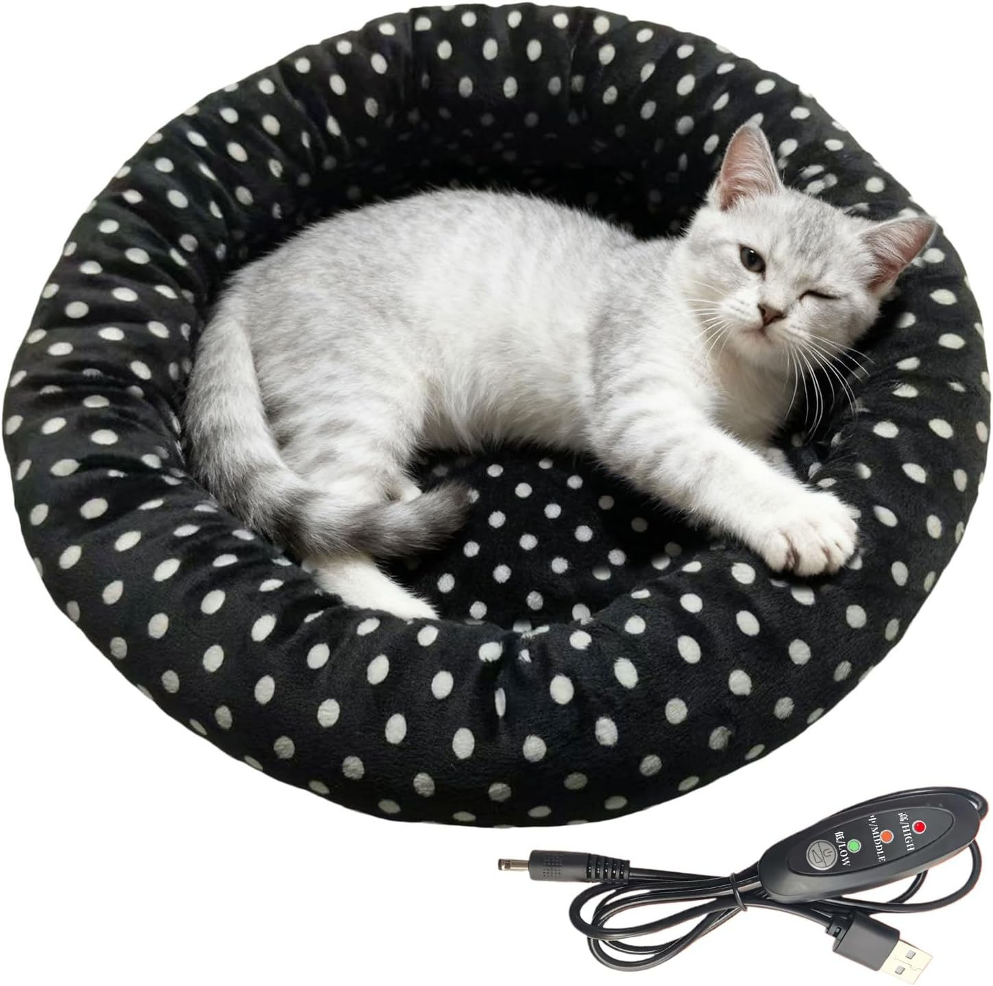 Eine Katze liegt in einem schwarz-weißen gepunkteten Bett mit einem Temperaturregler.
