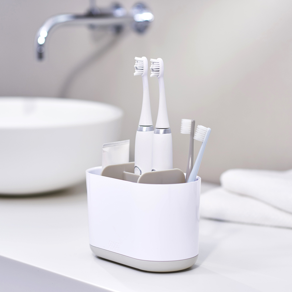 Un soporte blanco para cepillos de dientes con dos cepillos eléctricos y dos manuales.