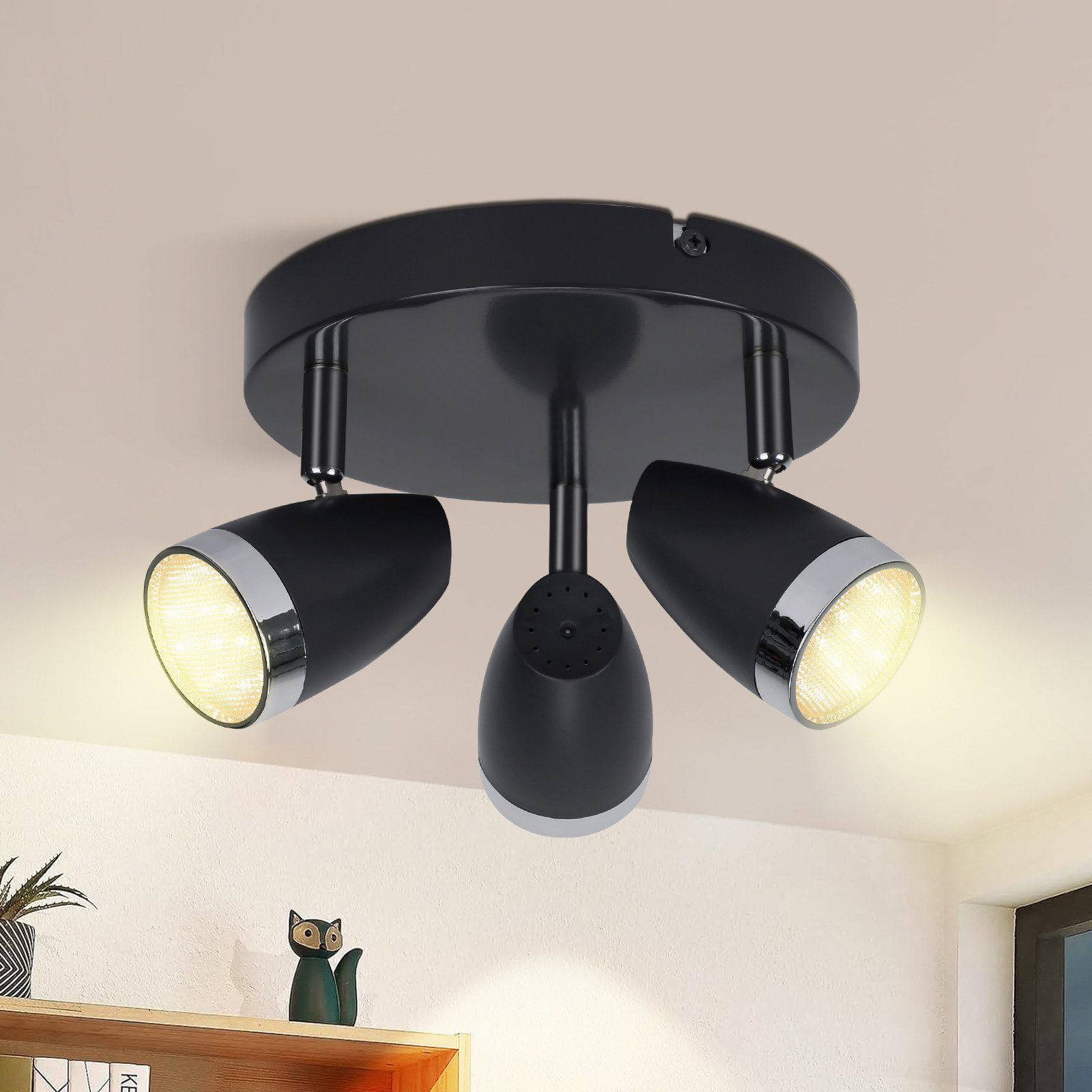 Lampada da soffitto nera con tre faretti orientabili e accenti argentati.
