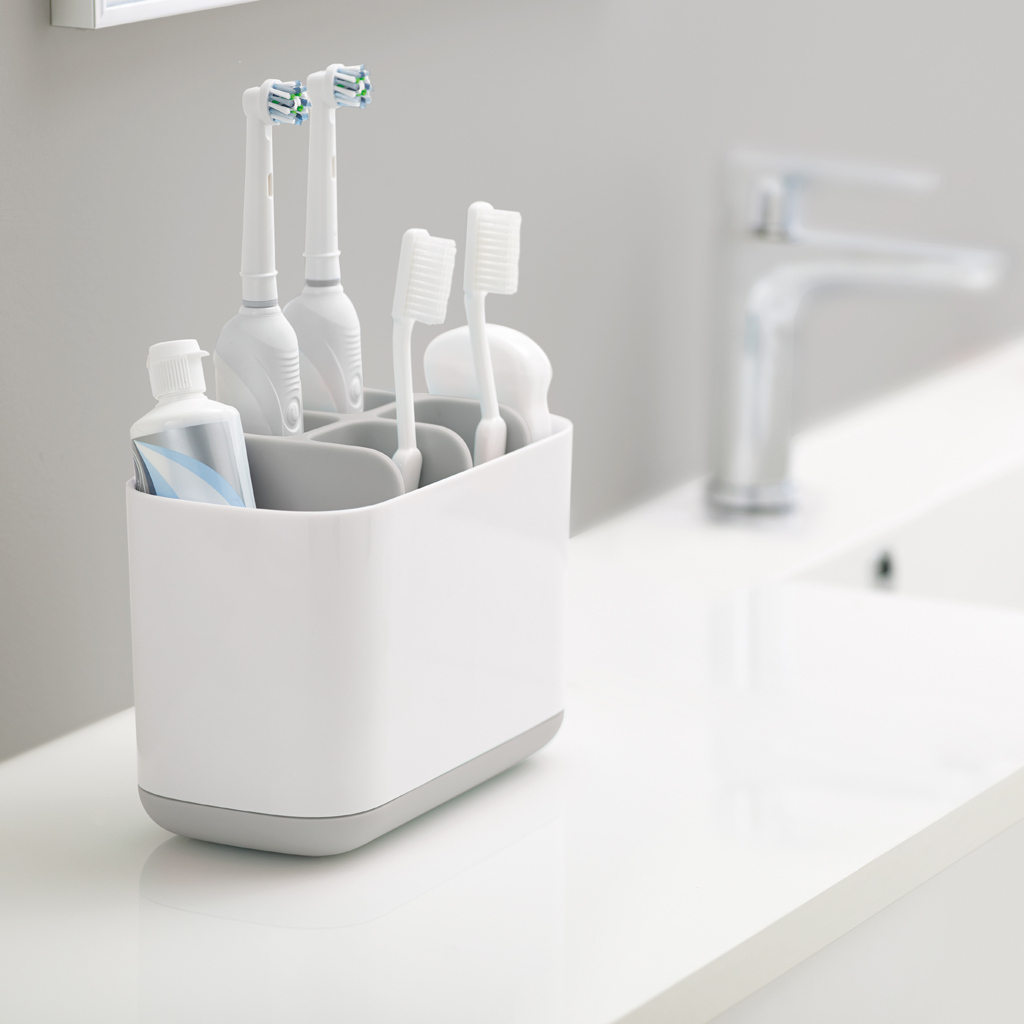 Un porta spazzolino bianco con dentifricio e sapone su un piano di lavoro.