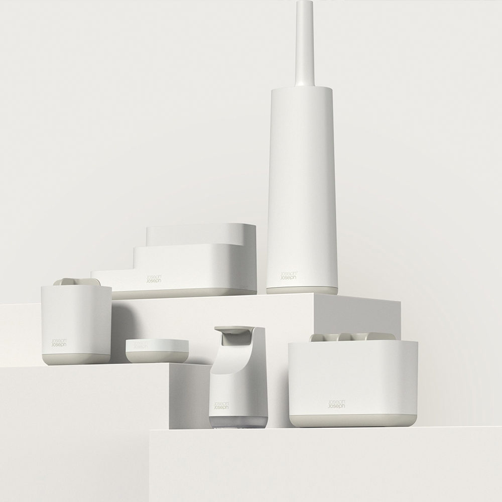 Accesorios de baño blancos de Joseph Joseph sobre un escenario blanco.