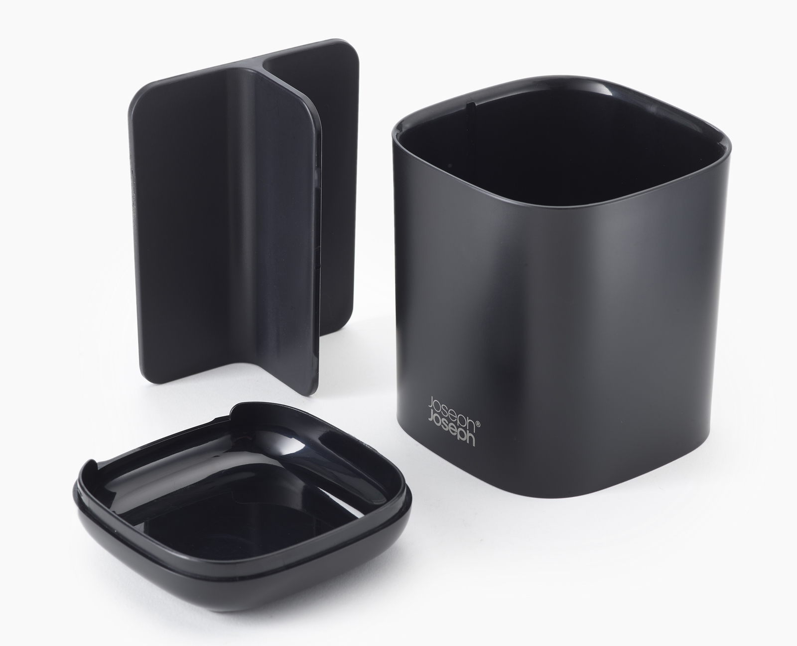 Tres accesorios de baño Joseph Joseph negros: un soporte, un contenedor y una tapa.
