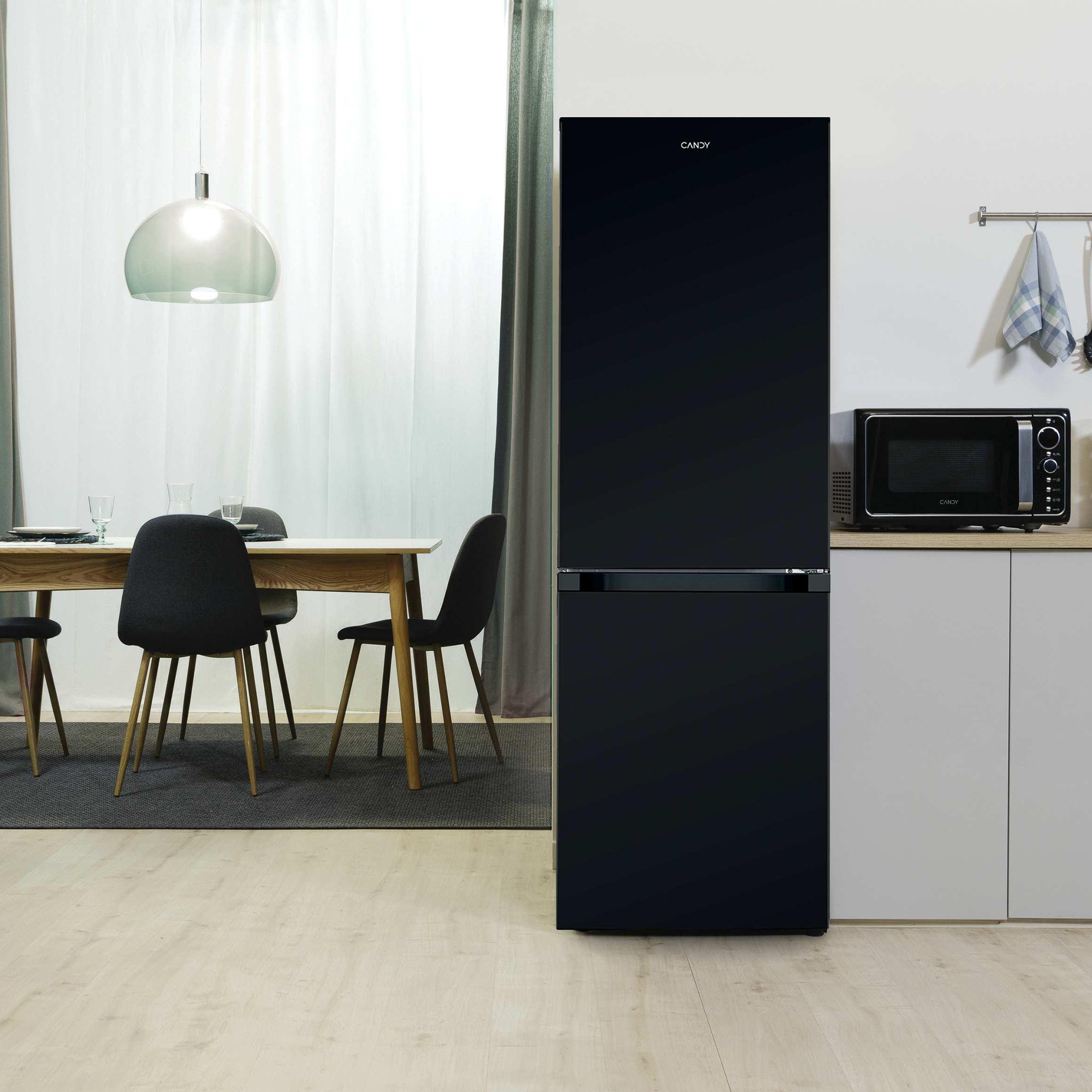 Ein schwarzer Kühlschrank und eine Mikrowelle stehen in einer modernen Küche neben einem Esstisch.