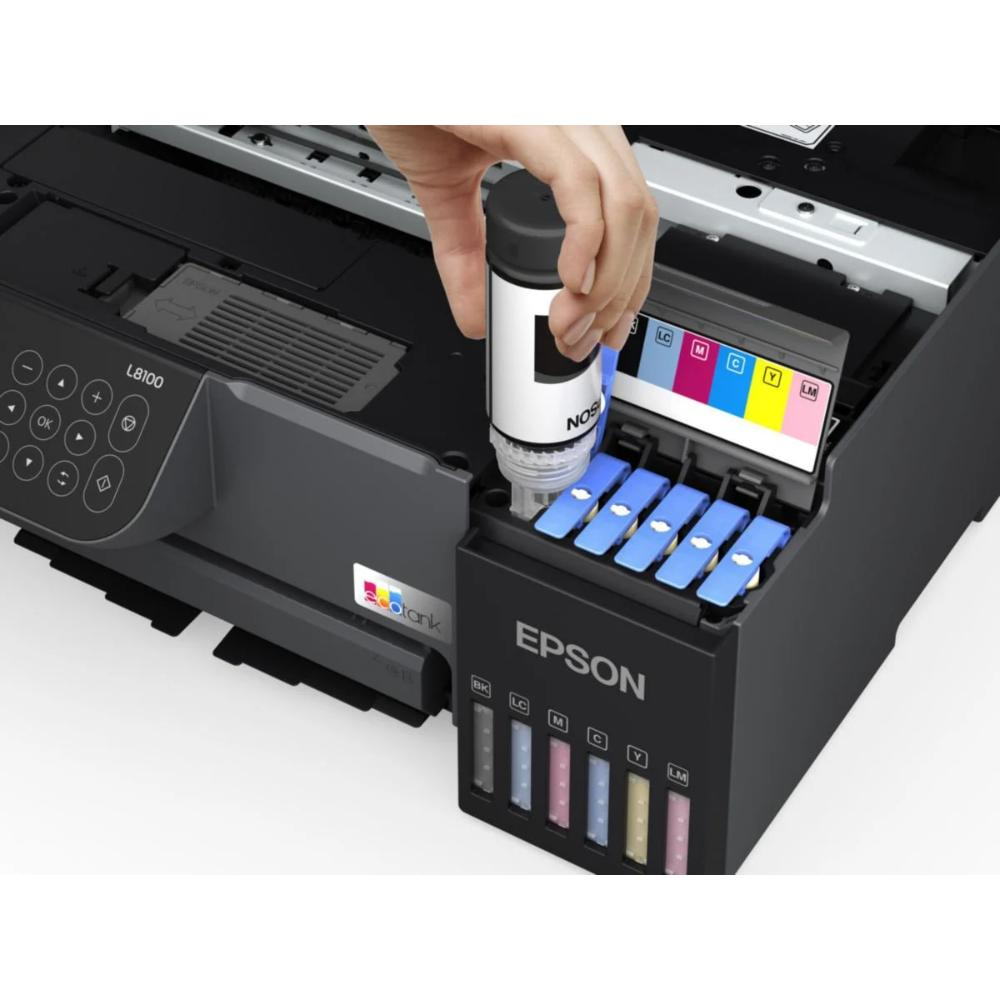 Bir el Epson yazıcıya mürekkep dolduruyor. Birkaç mürekkep şişesi görülüyor.
