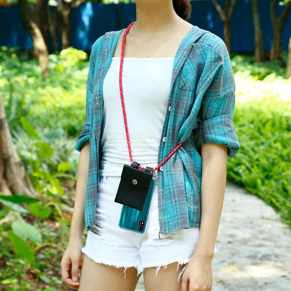 Persona con camicia a quadri blu, top bianco e pantaloncini bianchi, con telefono e piccolo portafoglio su cordino rosso.