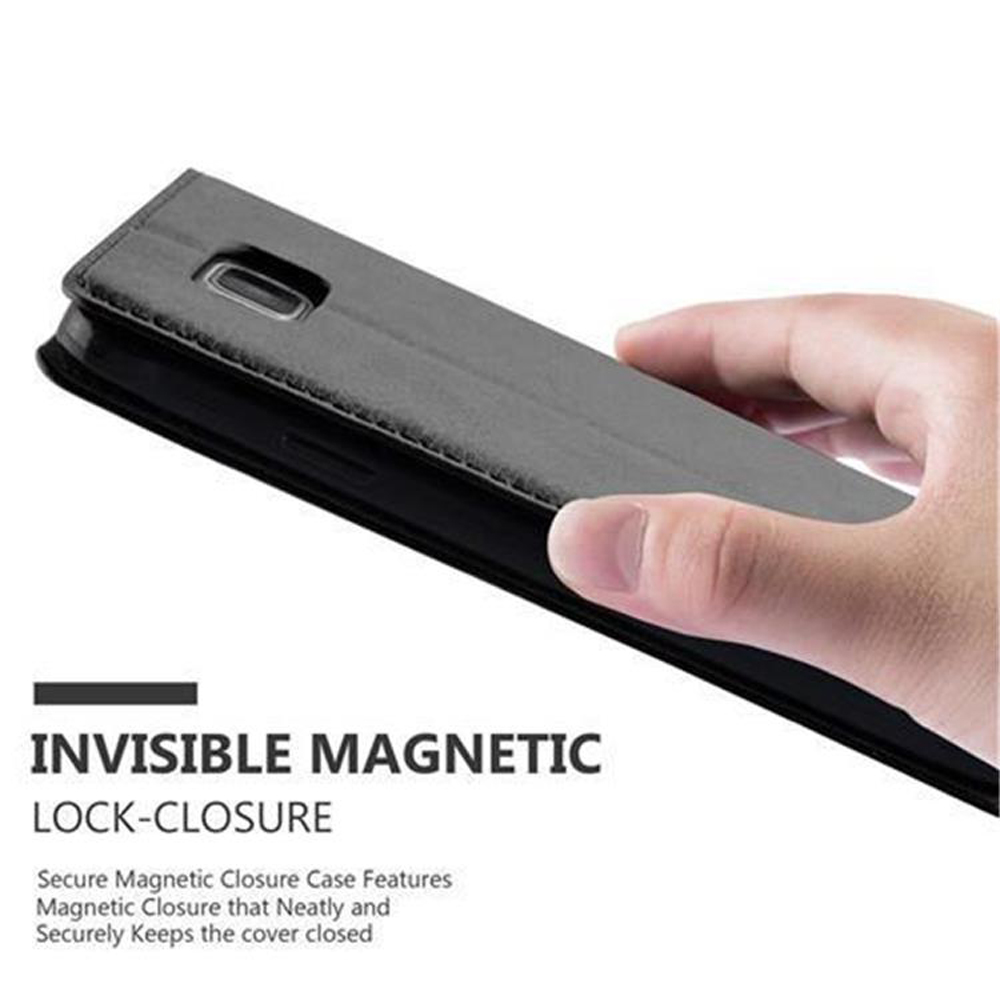 Una mano sostiene una funda tipo libro gris para teléfono. Vista cercana.