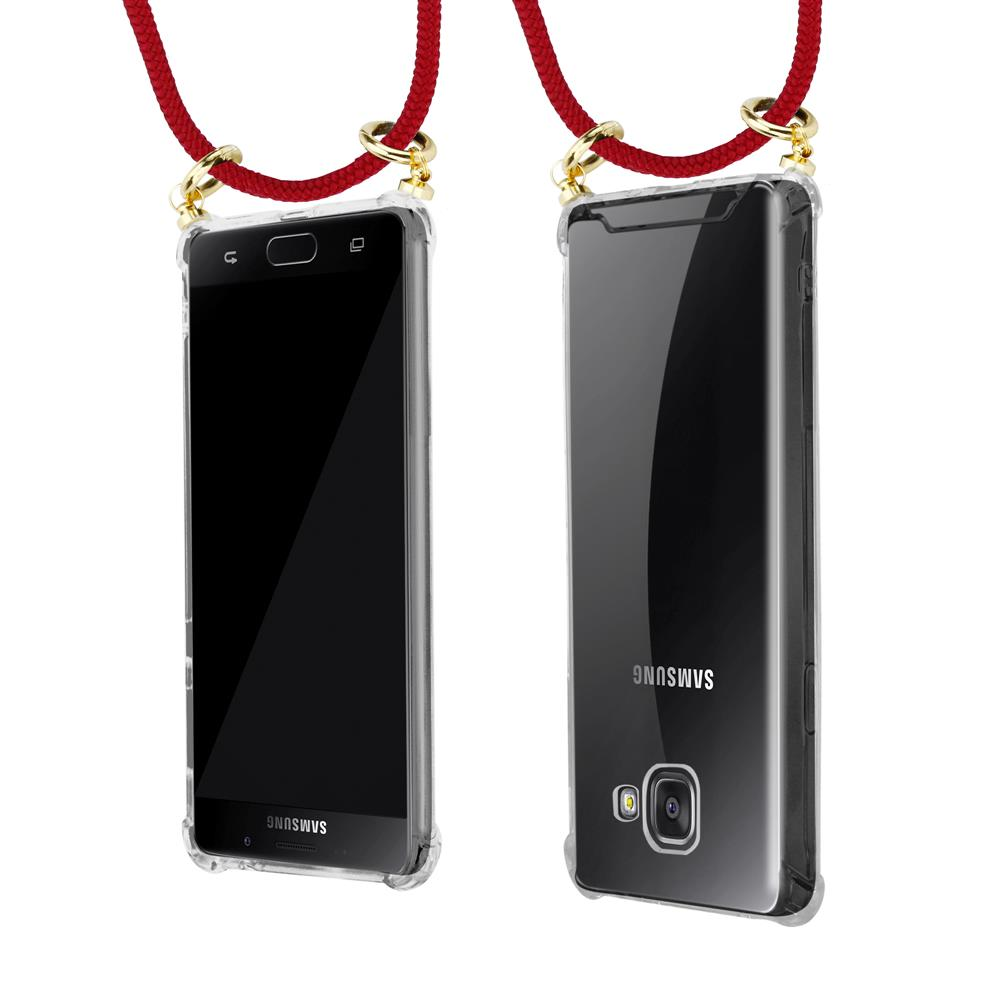 Un teléfono Samsung transparente con cordón rojo y anillos dorados.