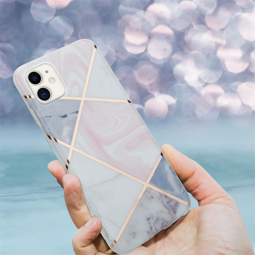 Una mano tiene uno smartphone con cover effetto marmo e linee oro rosa.