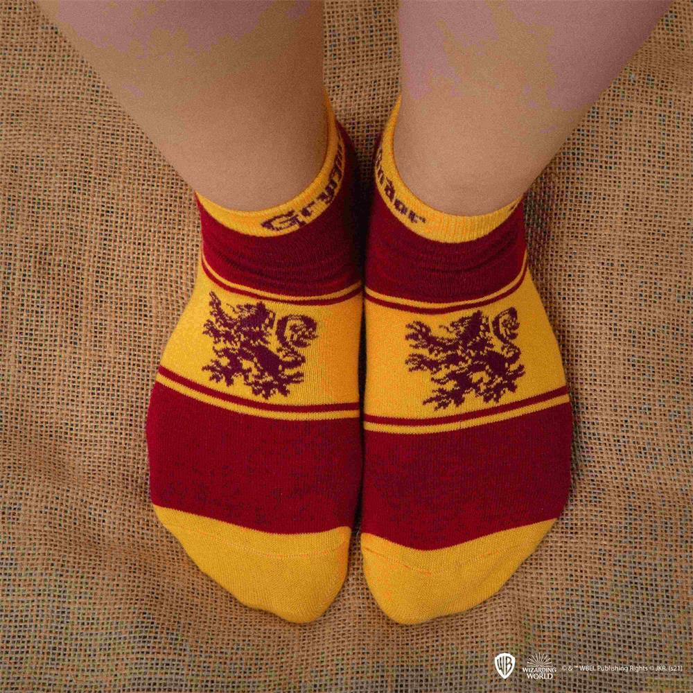 Rote und gelbe Socken mit Gryffindor-Löwen und Streifen auf Jute.