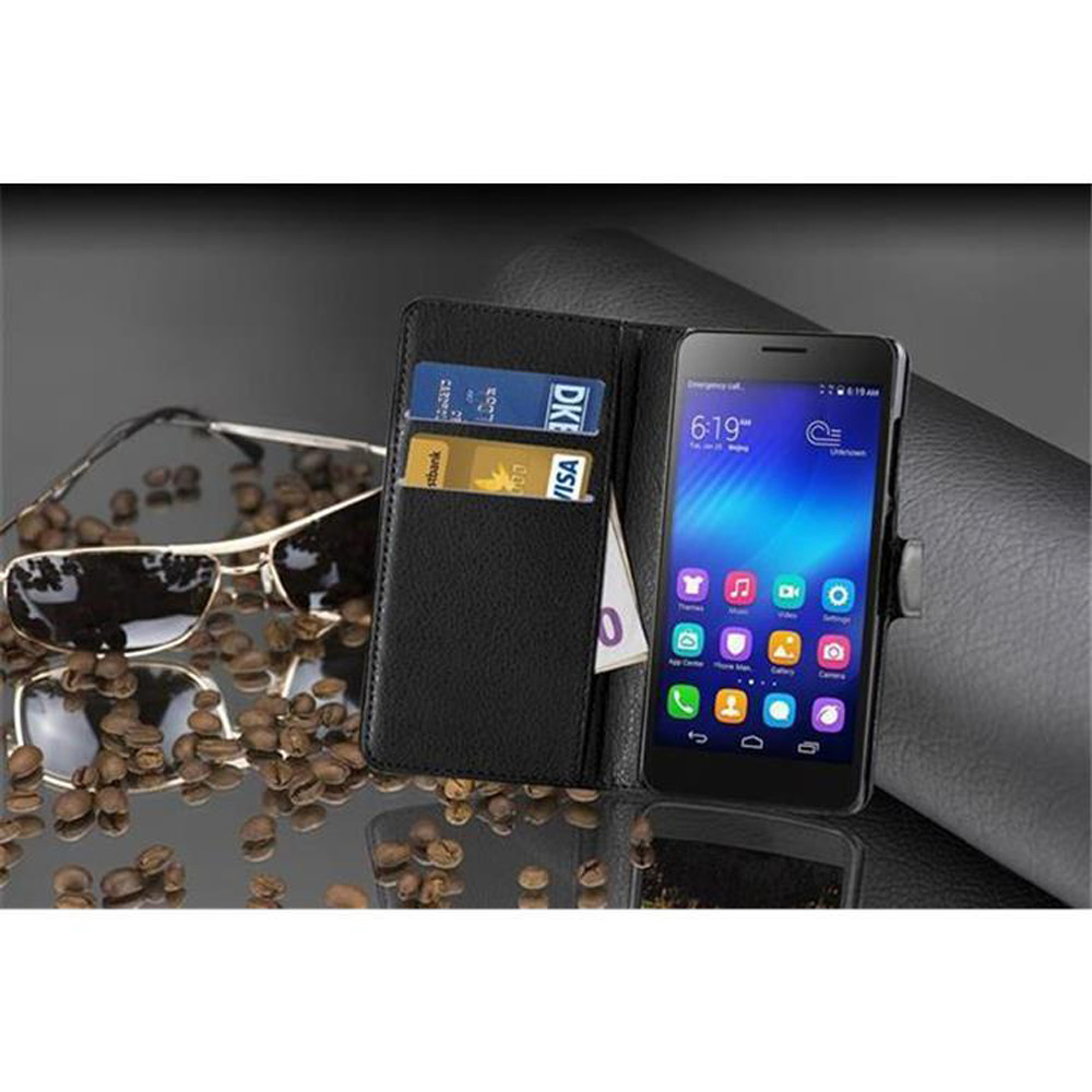 Uno smartphone nero in un portafoglio con carte, accanto a chicchi di caffè e occhiali da sole.