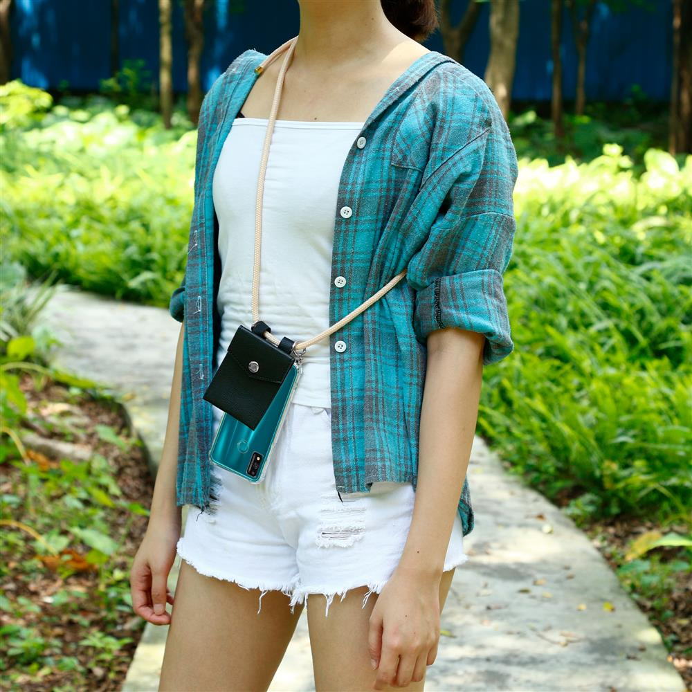 Una donna con camicia a quadri blu, top bianco e shorts bianchi indossa una custodia per telefono al collo.