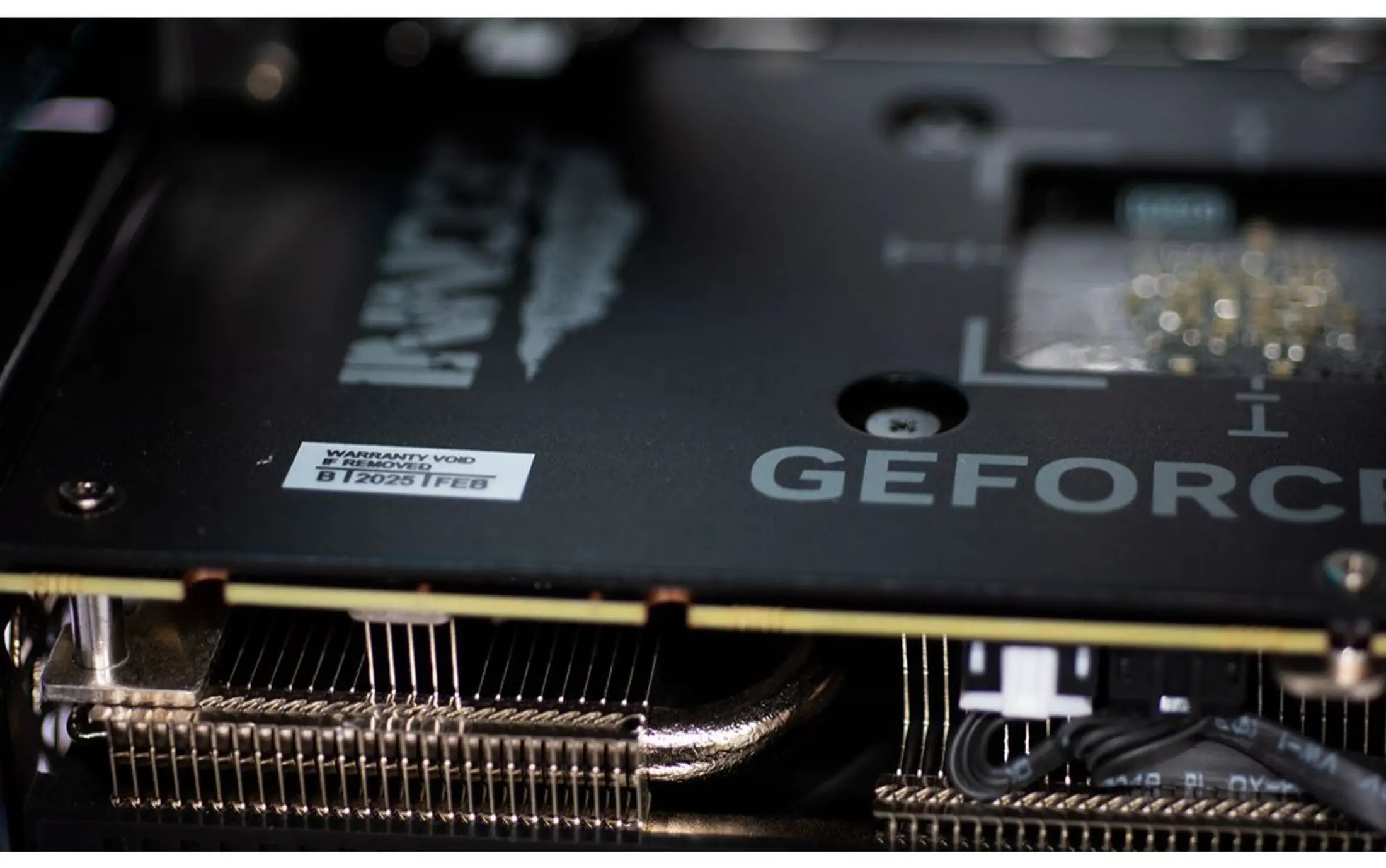 Close-up of a graphics card with "GEFORCE" logo and warranty sticker.