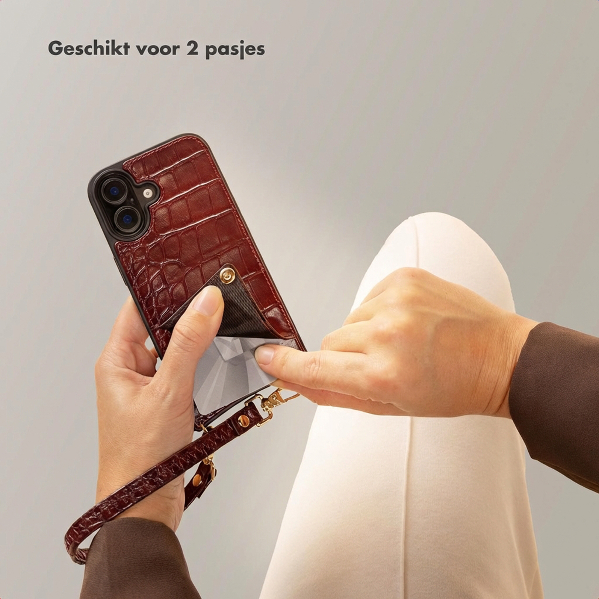 Une main tient une coque de téléphone rouge façon croco avec un fermoir argenté.