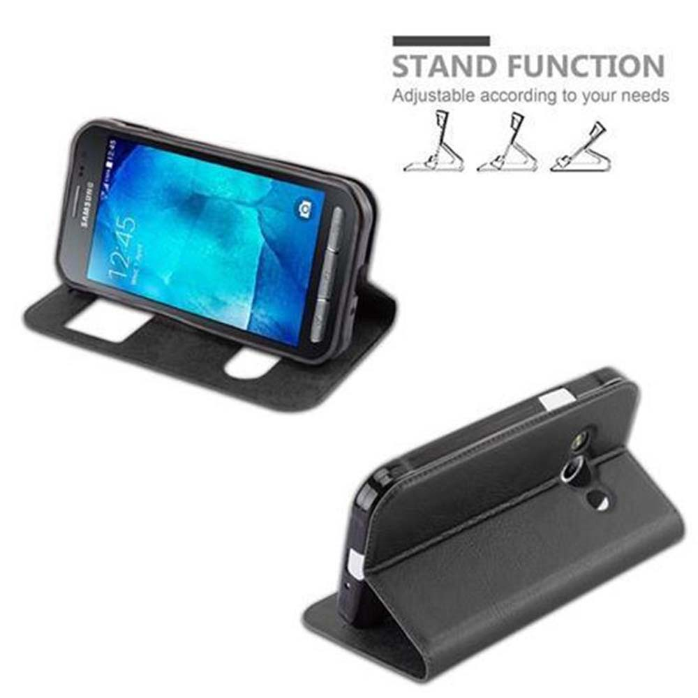Un telefono nero in una custodia a flip, funzionante come supporto.