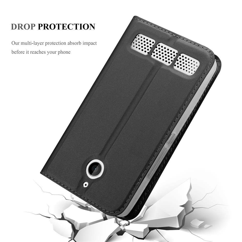 Funda de teléfono negra con orificios para altavoces cayendo sobre suelo agrietado.
