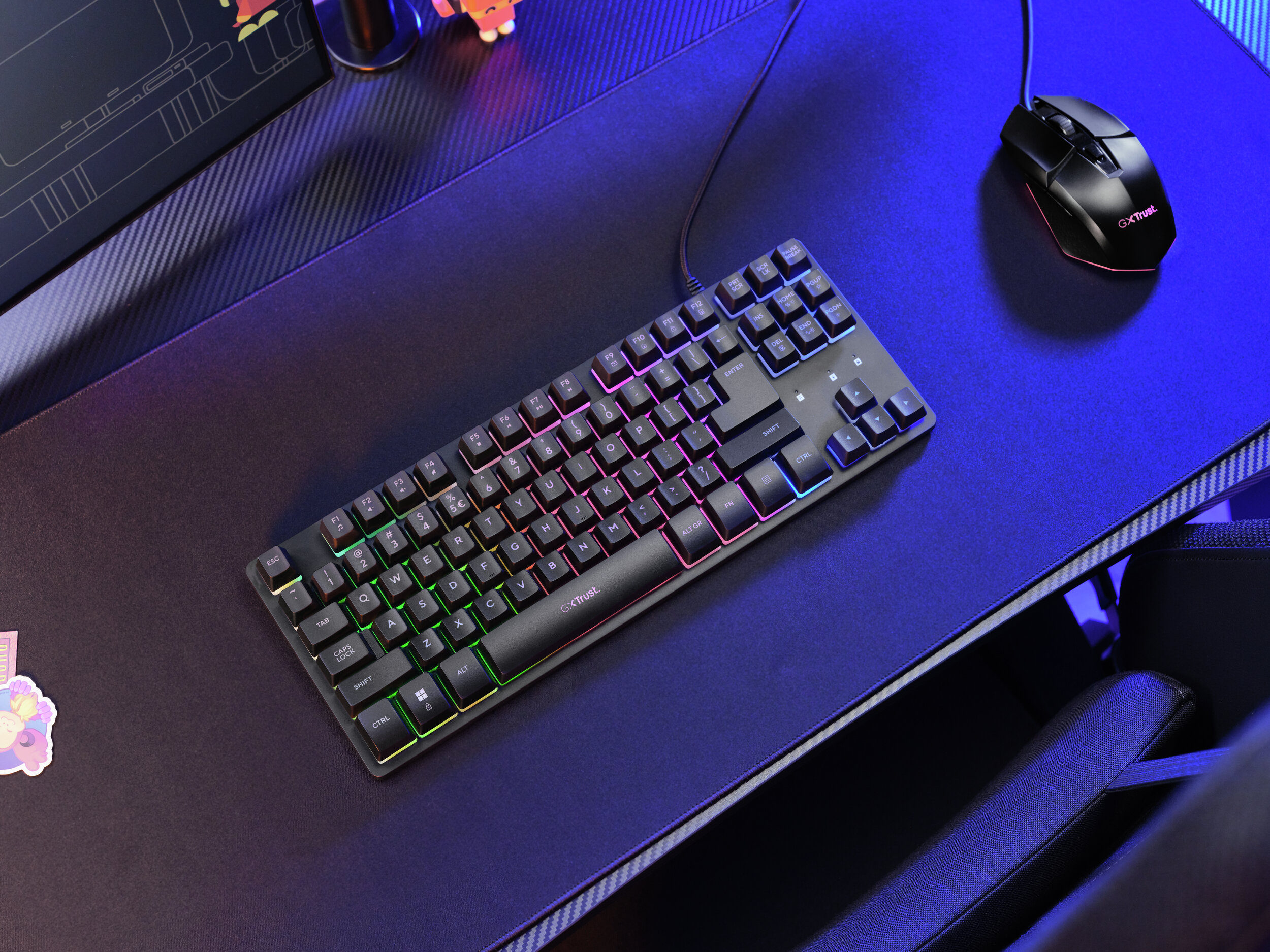 Un teclado gaming con iluminación RGB y un ratón sobre una alfombrilla.