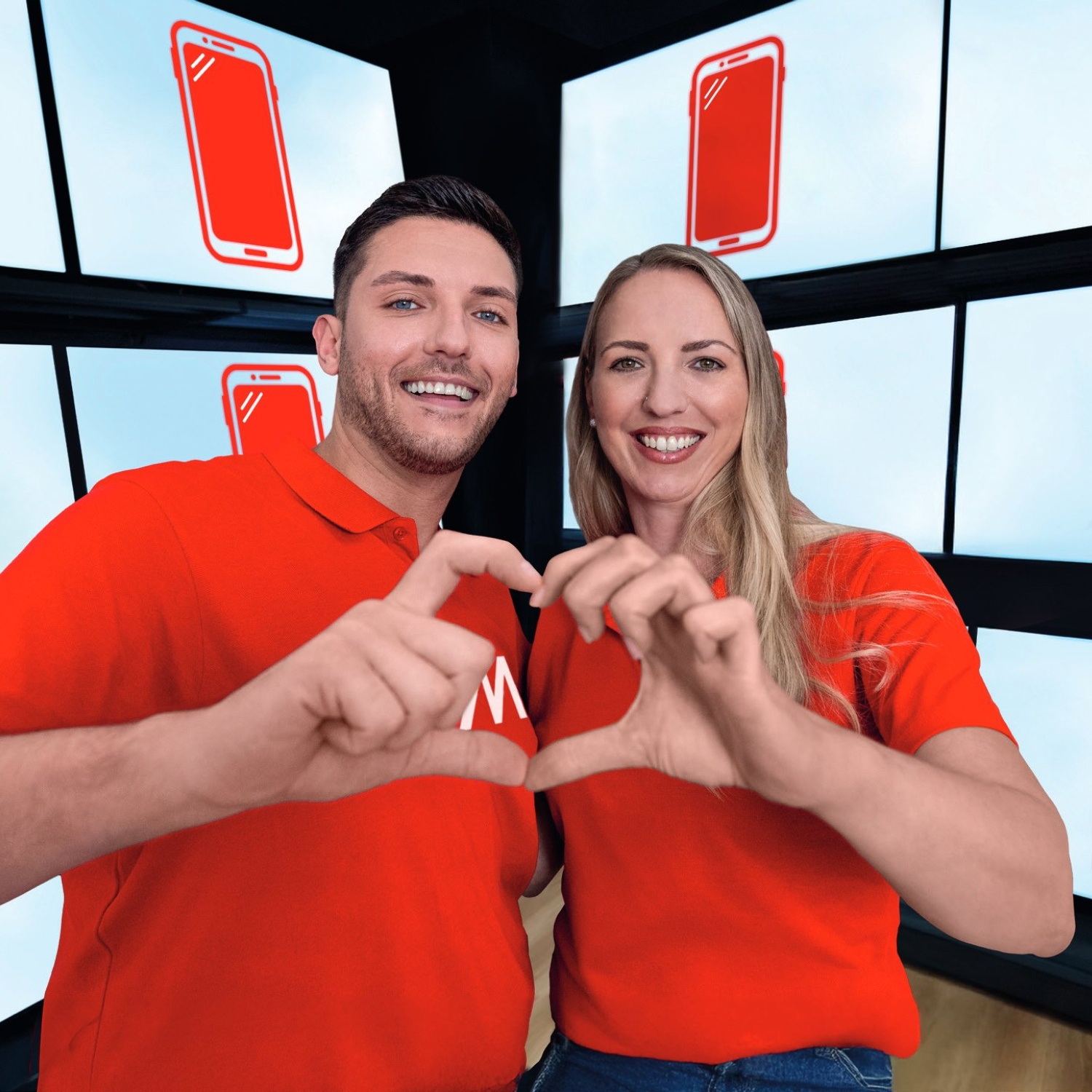 Mężczyzna i kobieta tworzą serce dłońmi przed ekranami z czerwonymi ikonami telefonów.