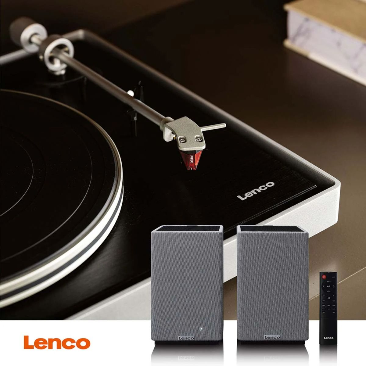 Gramofon z dwoma szarymi głośnikami i pilotem.