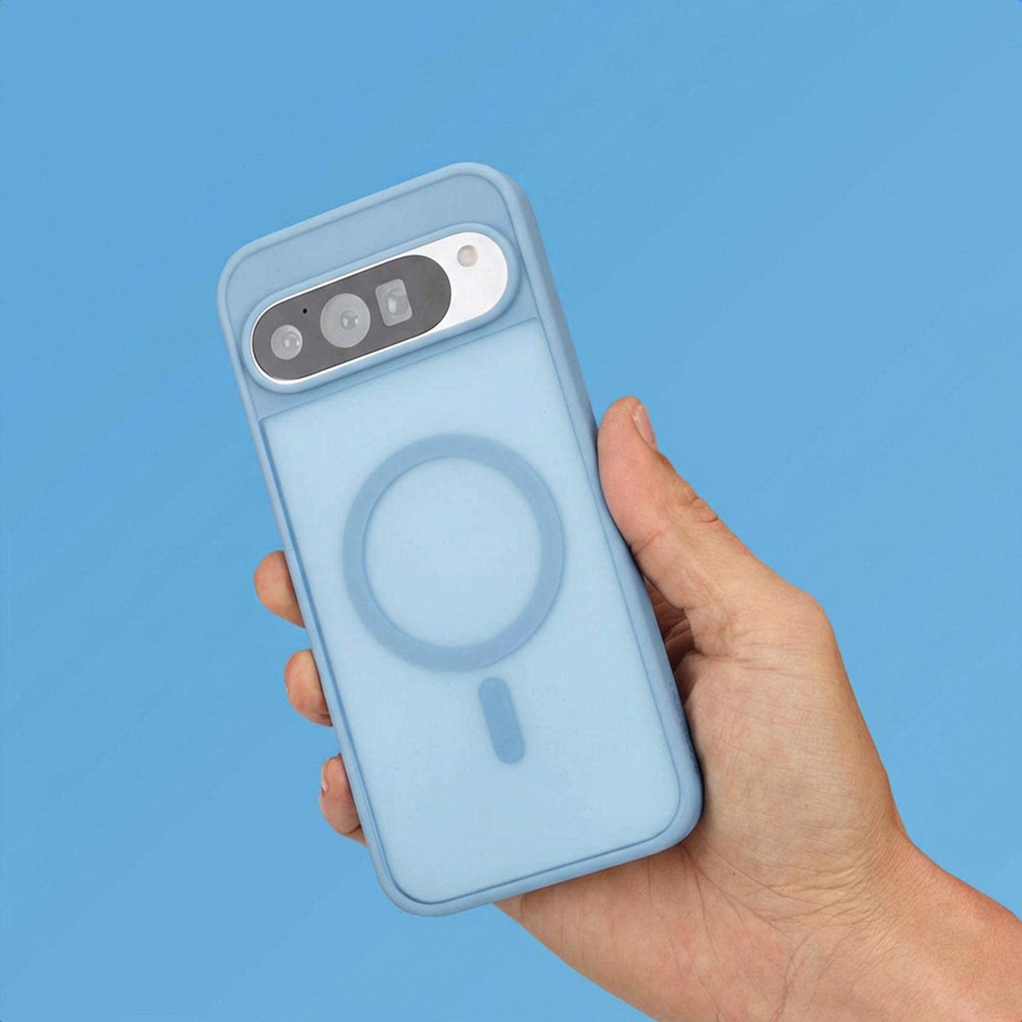 Een hand houdt een lichtblauwe telefoonhoes vast met cameramodule en magneetring.