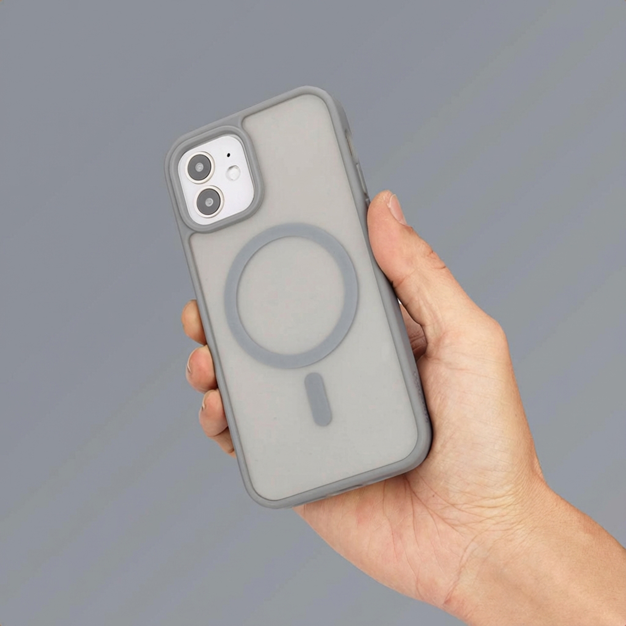 Een hand houdt een grijze telefoon vast met een hoesje met magneetring.