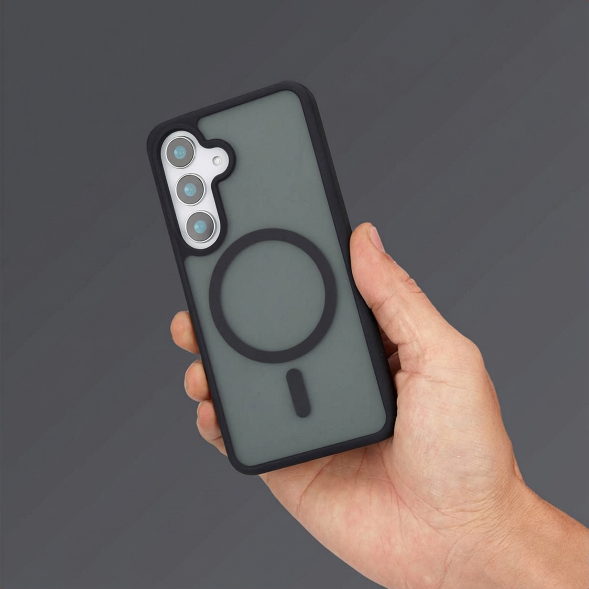 Una mano tiene una custodia per telefono verde scuro con tre fotocamere e anello magnetico.