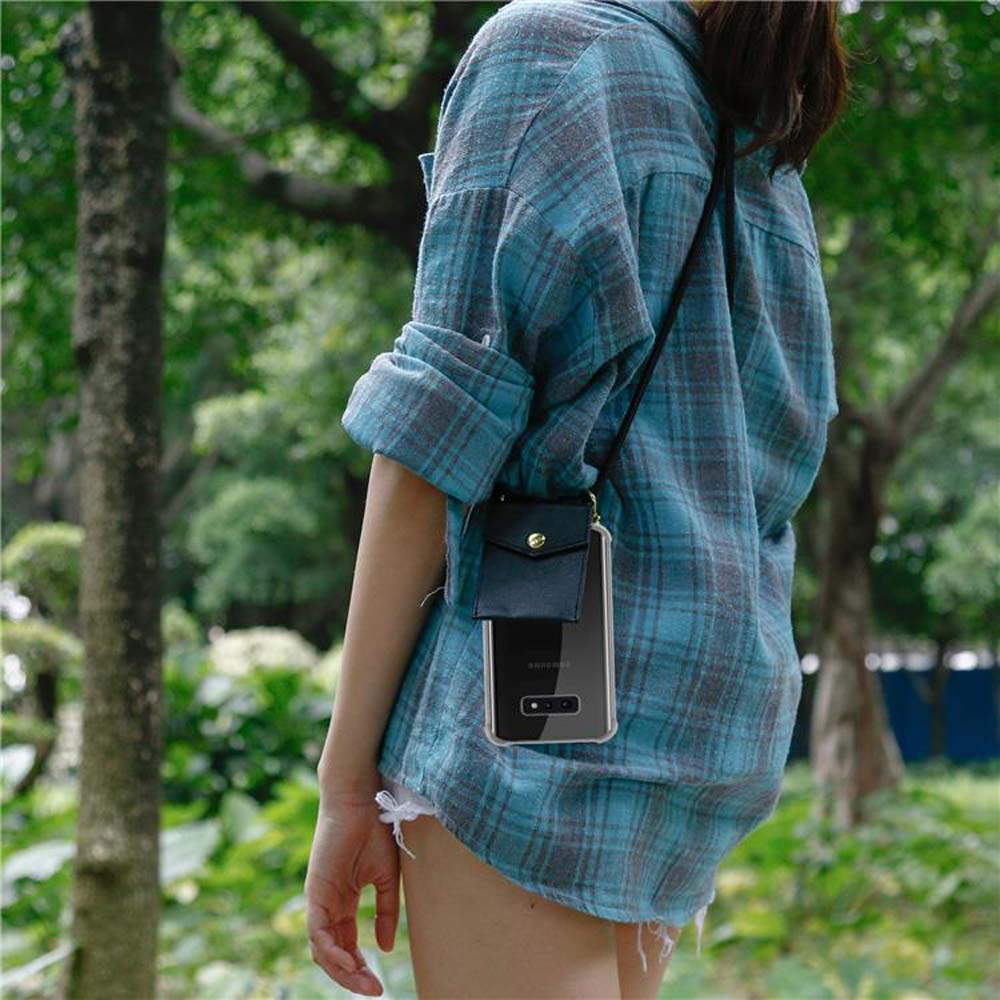 Donna con camicia a quadri indossa una custodia per telefono a tracolla. Alberi sullo sfondo.