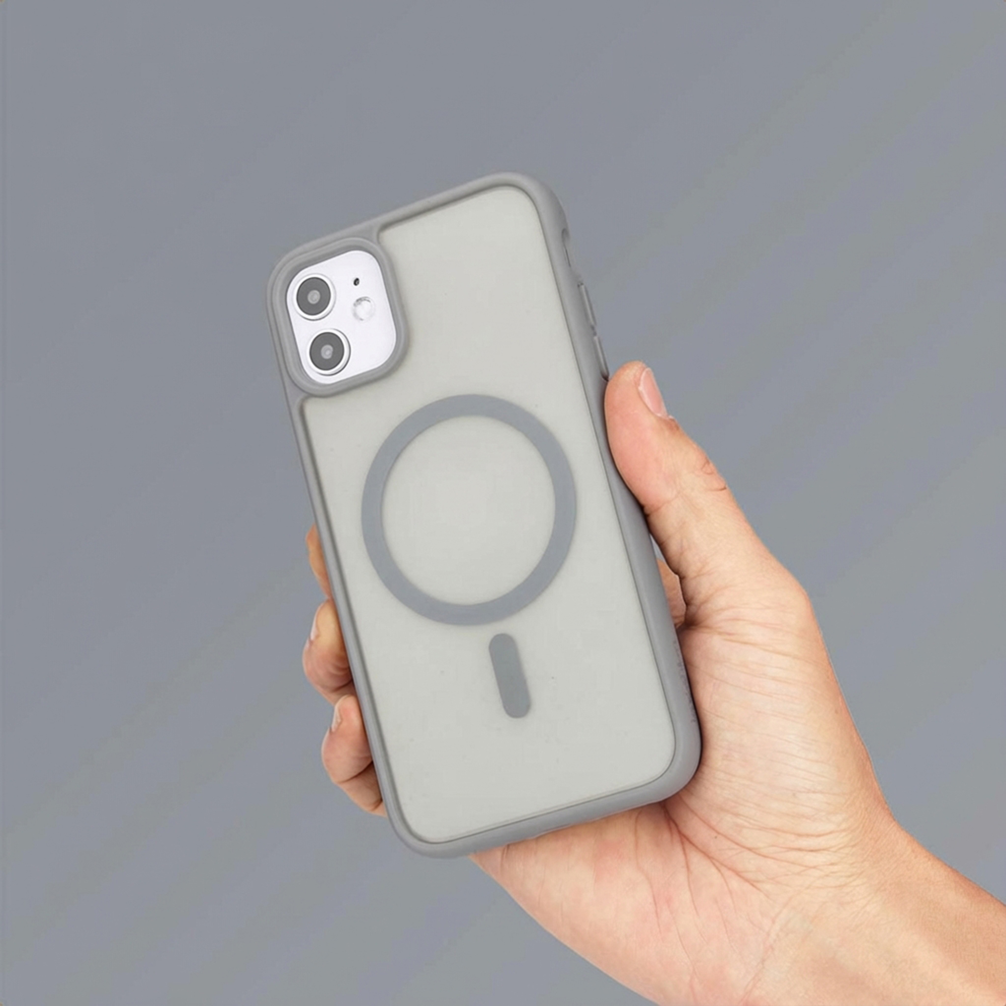 Een hand houdt een grijze telefoonhoes vast met een magnetische oplaadindicator.