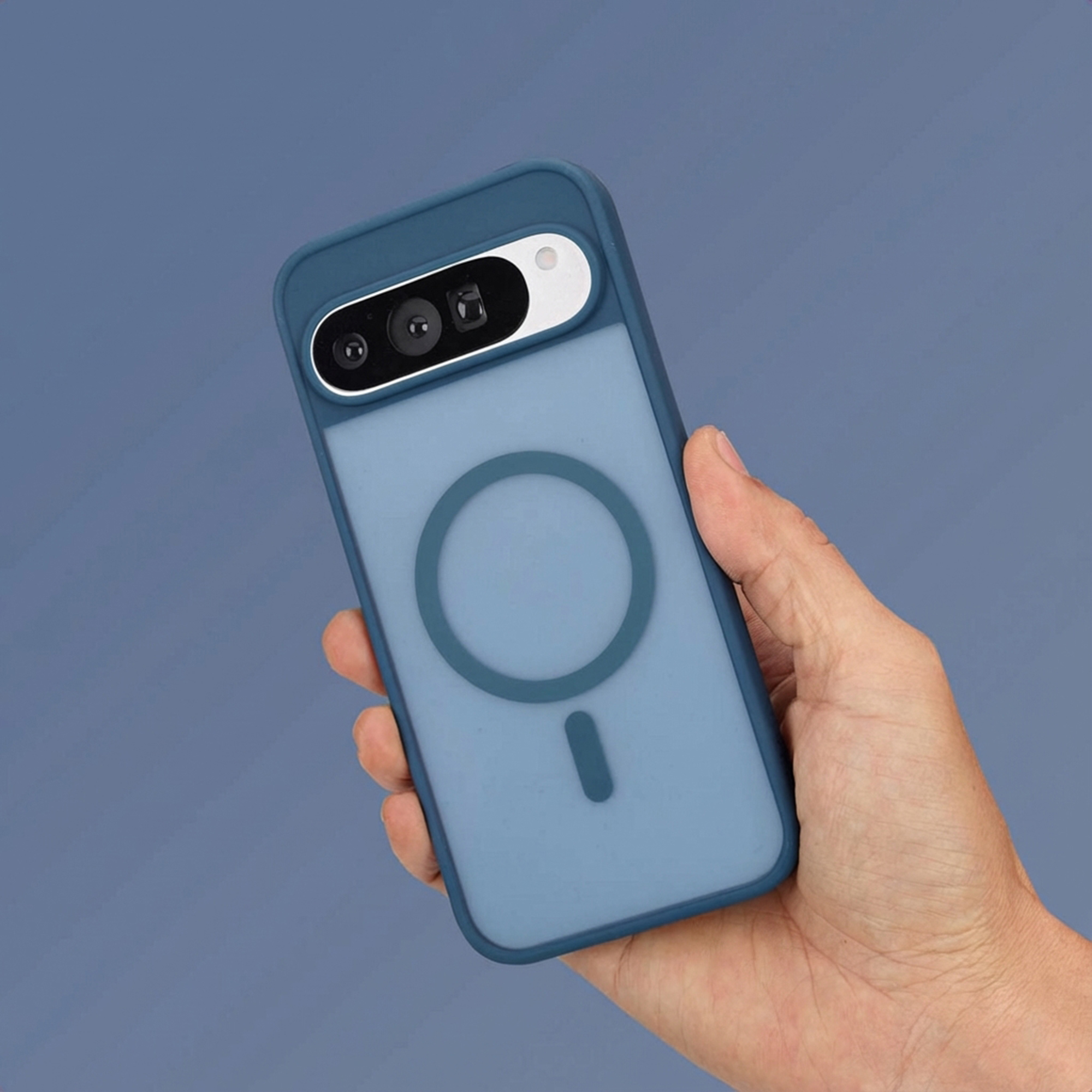 Een hand houdt een blauwe telefoonhoes met camera's en magneetring vast.