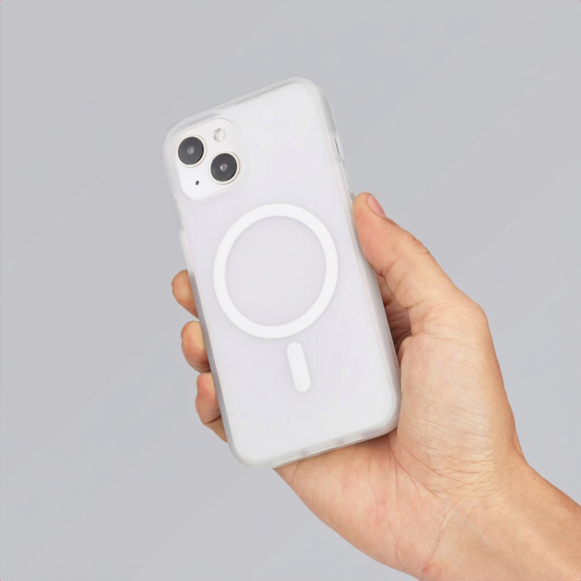 Een hand houdt een witte telefoon met MagSafe-ring vast.