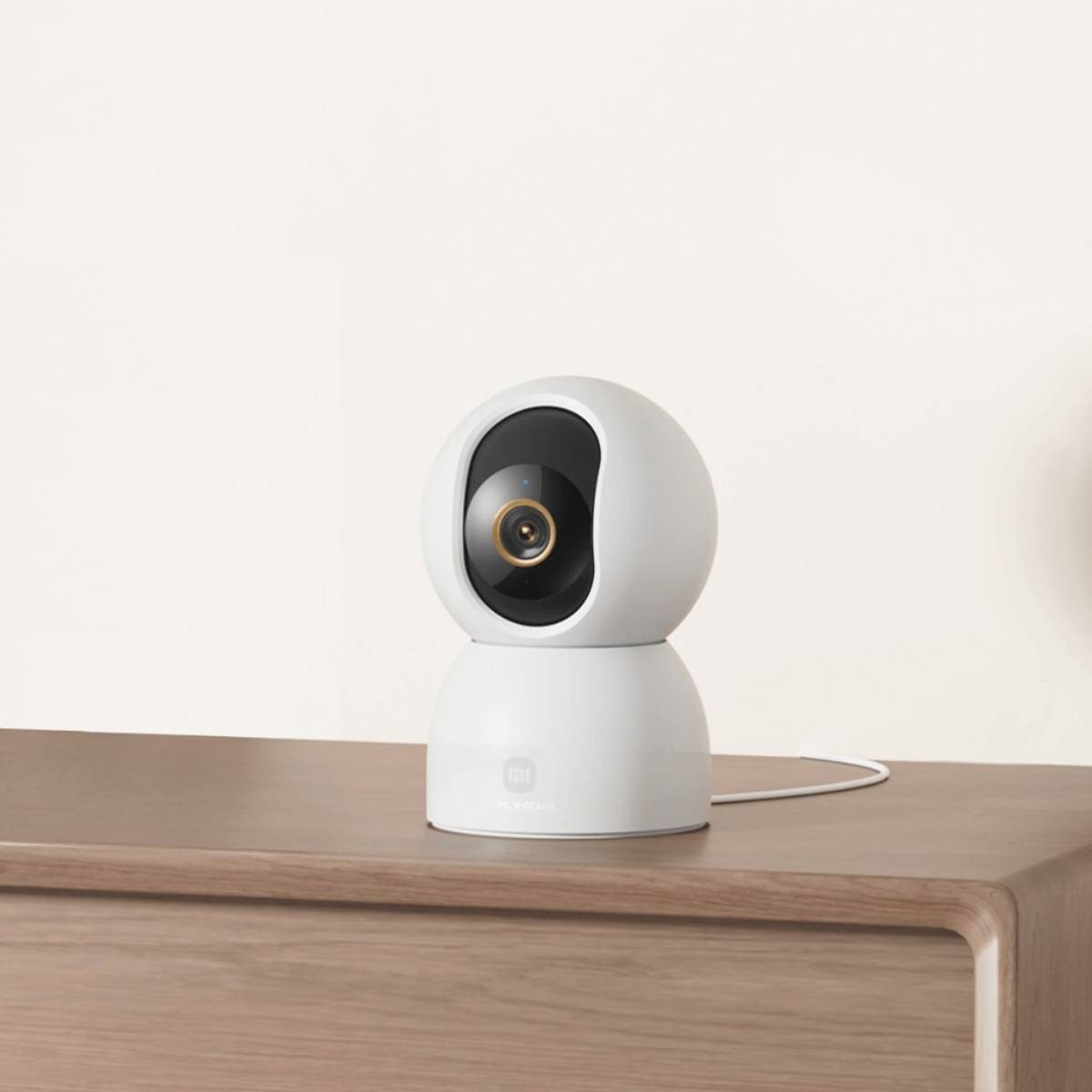 Biała kamera bezpieczeństwa z czarnym obiektywem na drewnianej powierzchni.