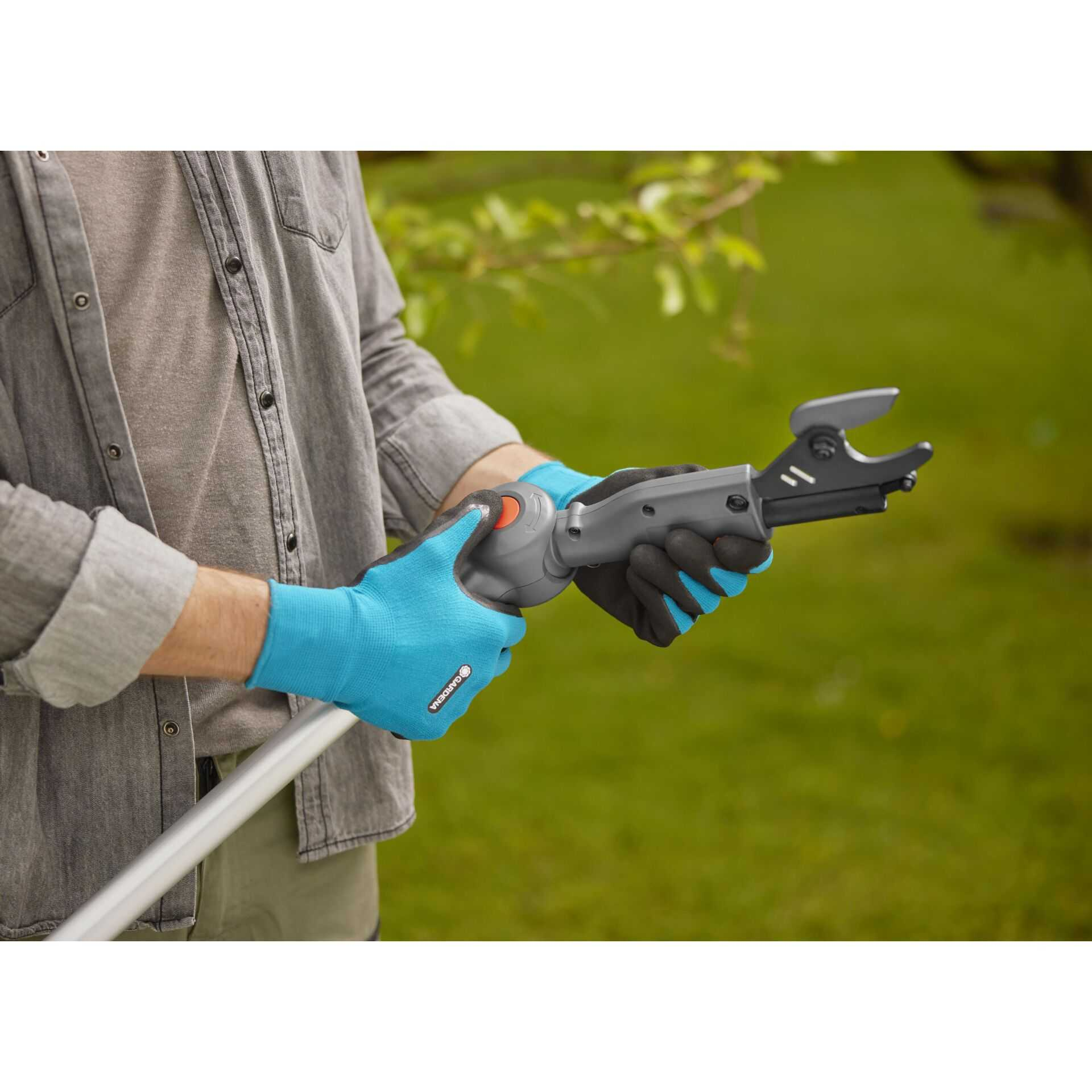 Mann in blau-schwarzen Handschuhen hält Gartenschere und Stiel.