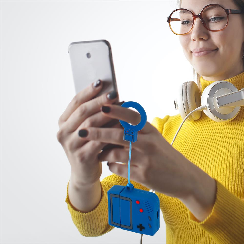 Frau mit Brille und Kopfhörern hält ein Smartphone und einen blauen Gameboy-Anhänger.