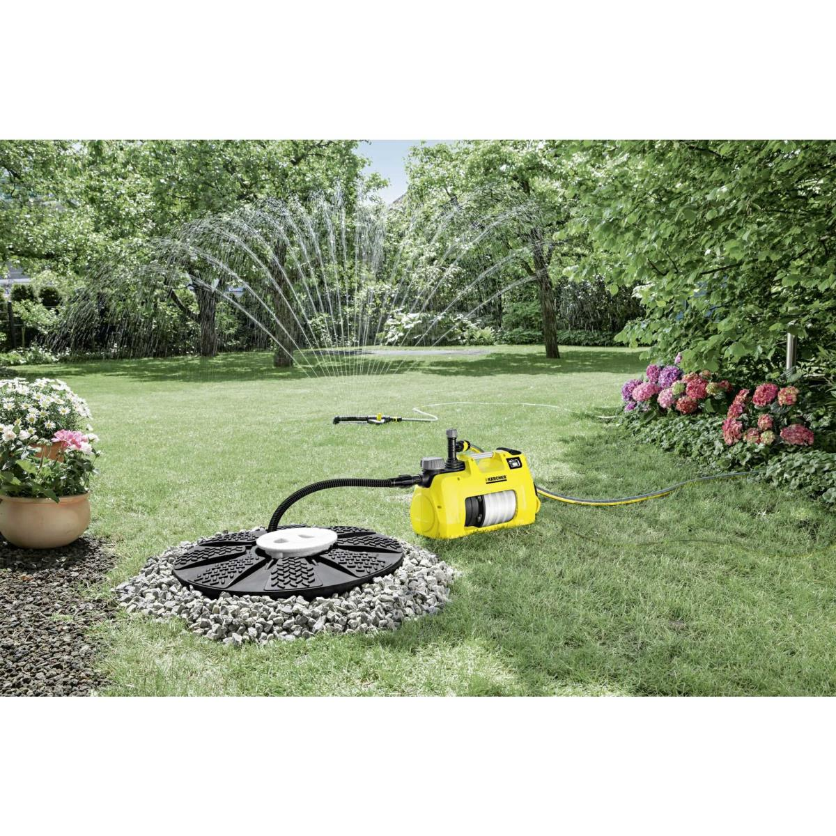 Una bomba Karcher amarilla riega un césped verde con un aspersor.