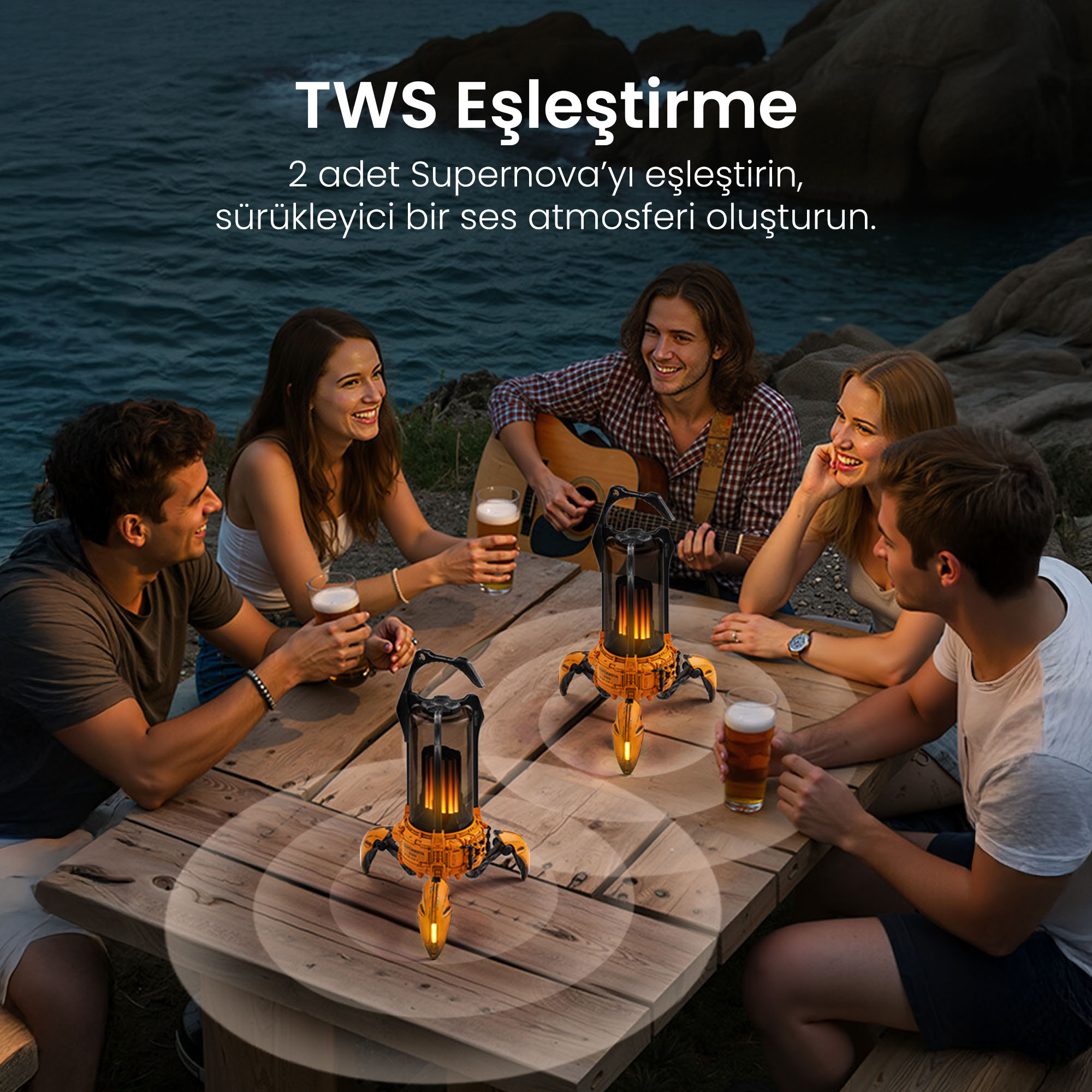 Przyjaciele siedzą przy stole z piwami, jeden gra na gitarze, dwa głośniki.