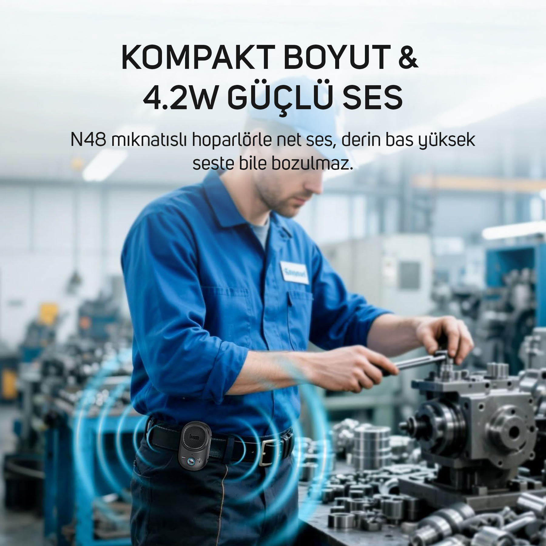 Mavi iş kıyafetli bir adam fabrikada makine tamir ediyor, kemerinde hoparlör var.