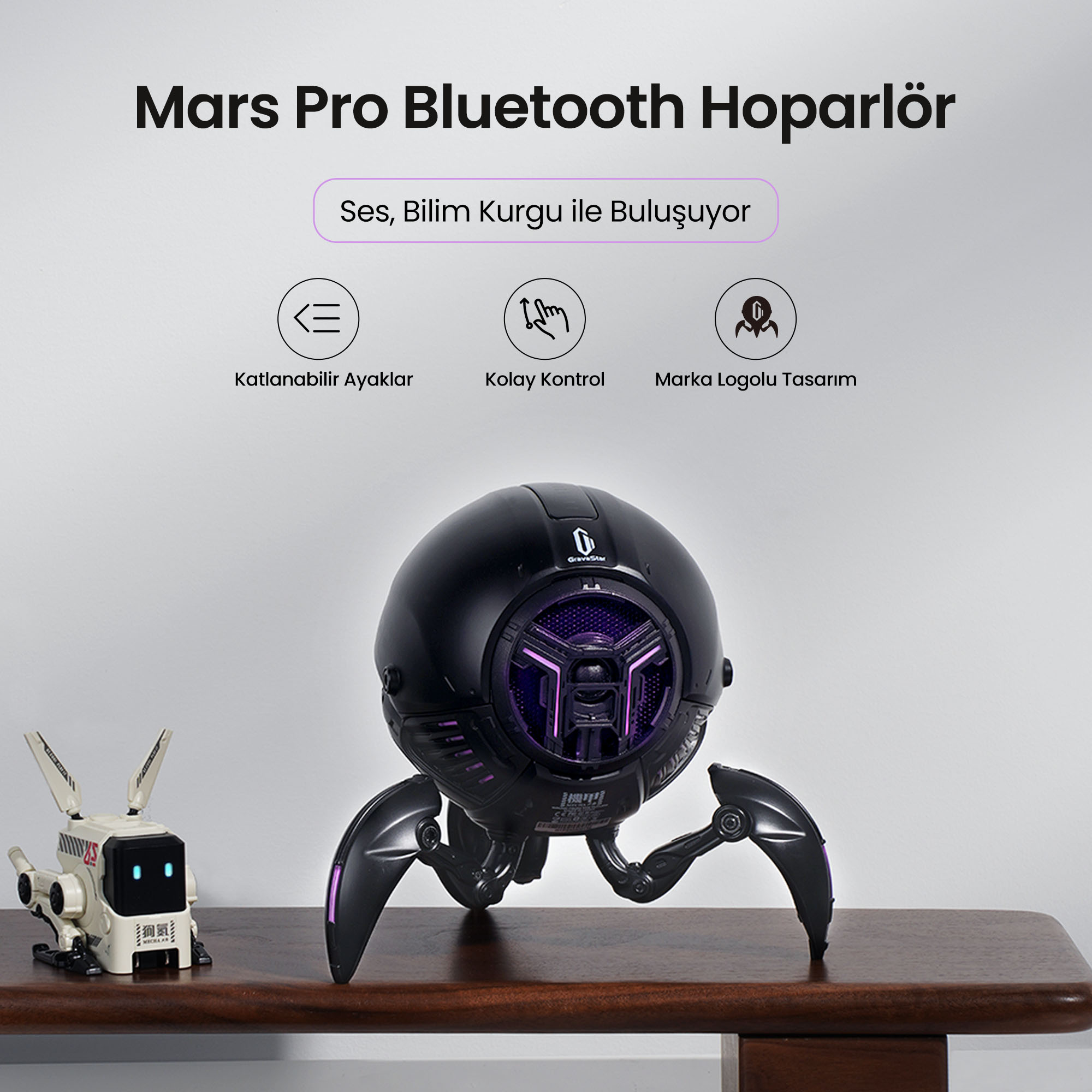 Mor ışıklı, örümcek şeklinde siyah hoparlör ve küçük bir robot.