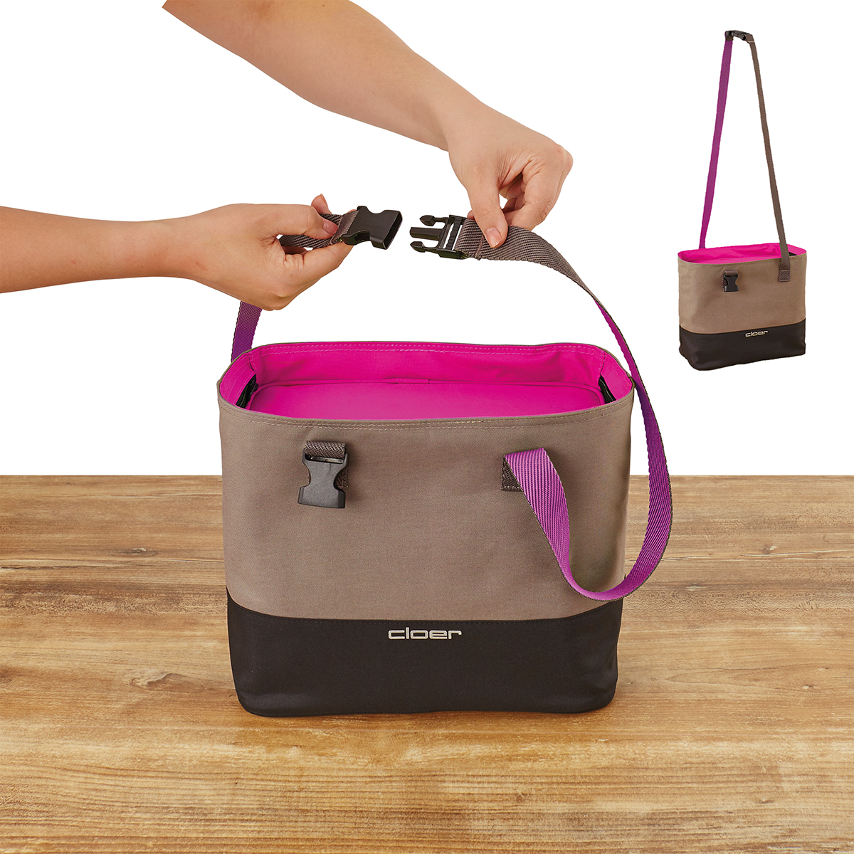 Graue Tasche mit pinkem Futter. Hände befestigen Riemen.