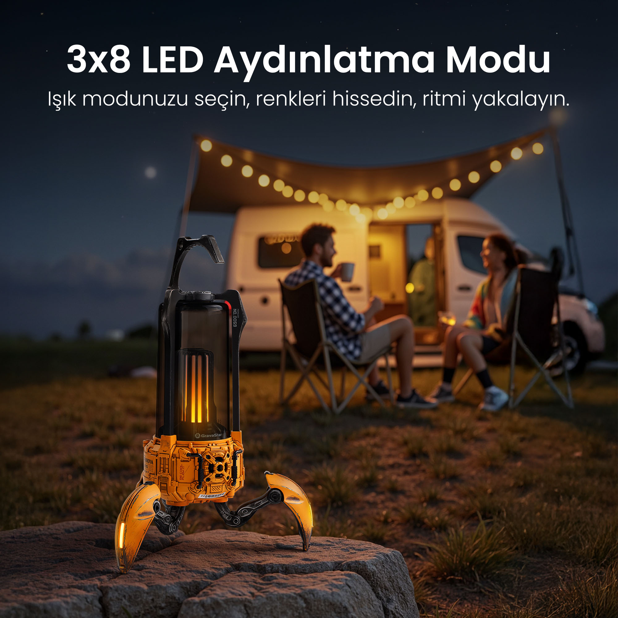 Pomarańczowy głośnik-robot na pierwszym planie. Ludzie siedzą przed kamperem w tle.