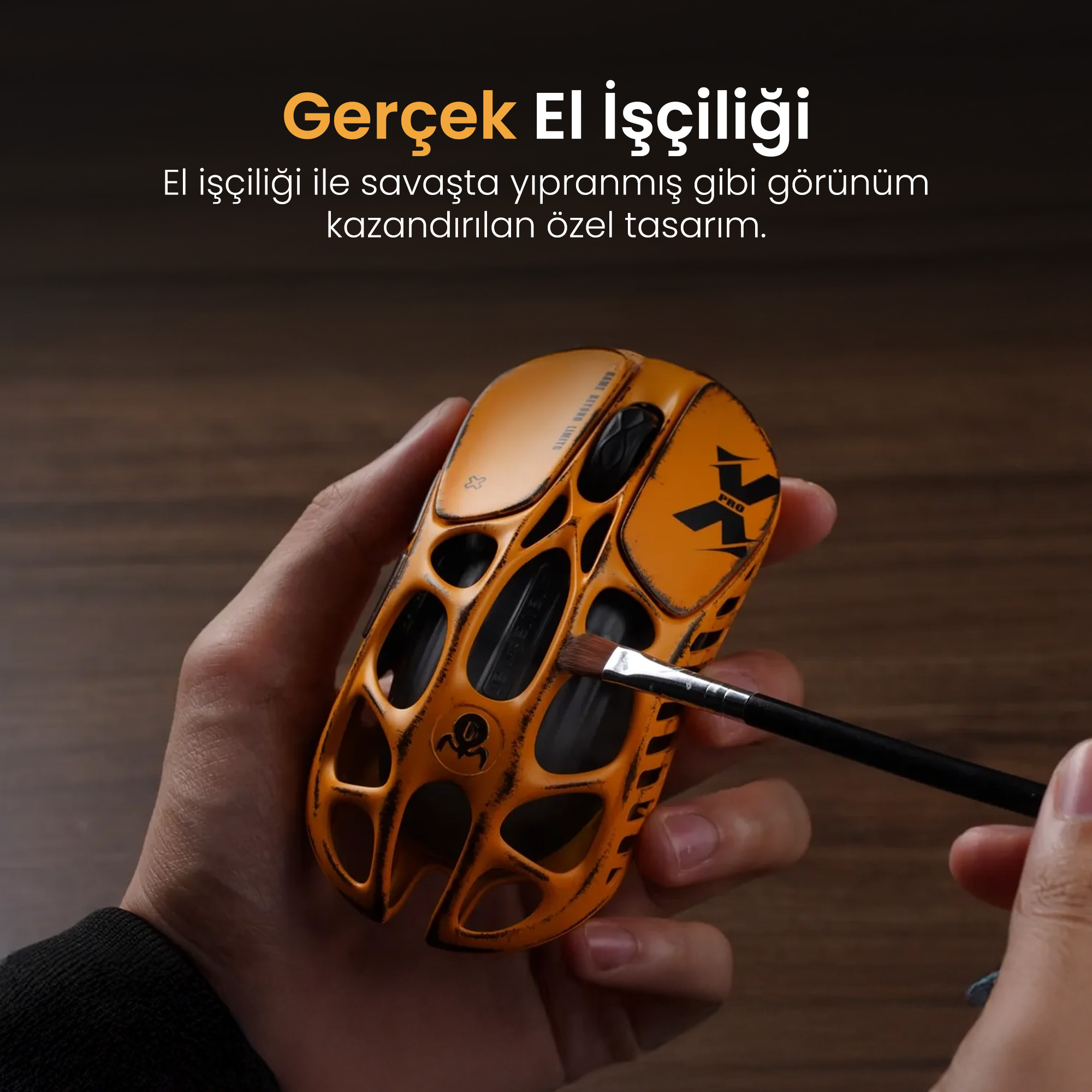 Pomarańczowa mysz z czarnym wzorem, trzymana przez dłoń z pędzlem.