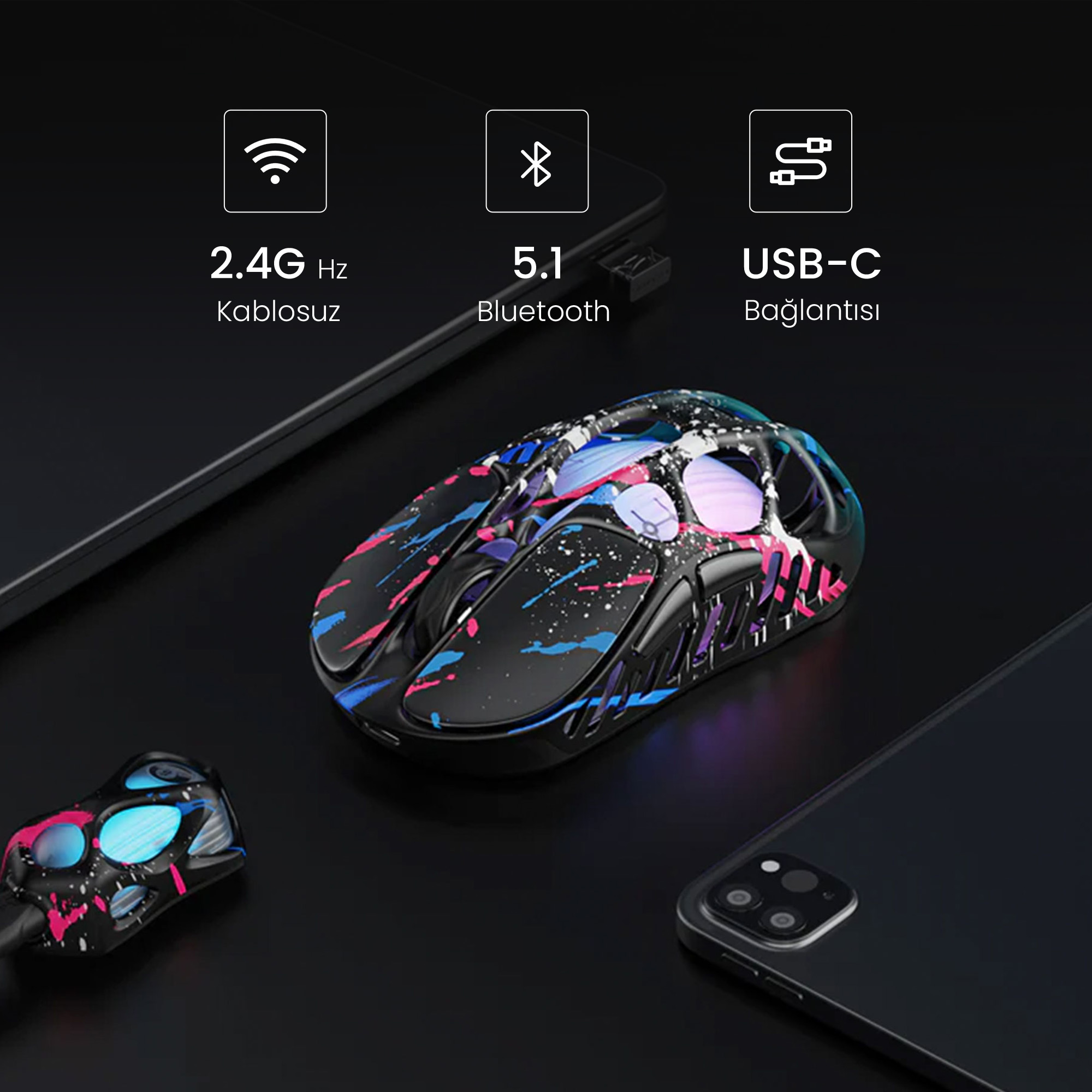 Czarna mysz z kolorowym wzorem plam farby, obok klucza USB-C i smartfona.