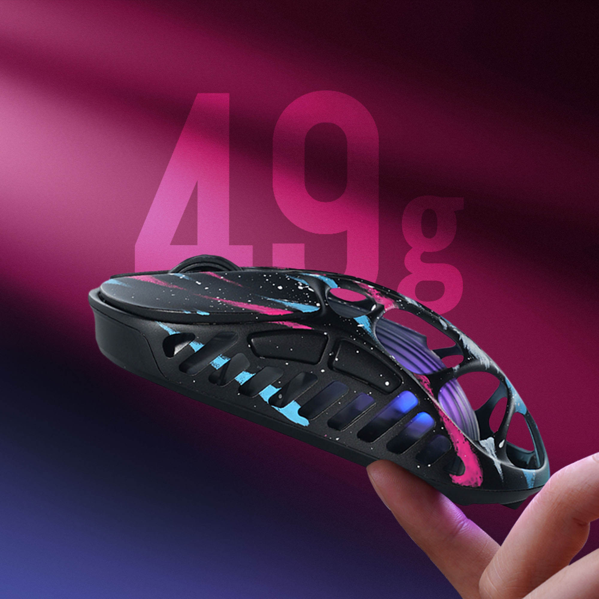 Czarna mysz z różowymi i niebieskimi akcentami, trzymana na palcu. Duże 49g.