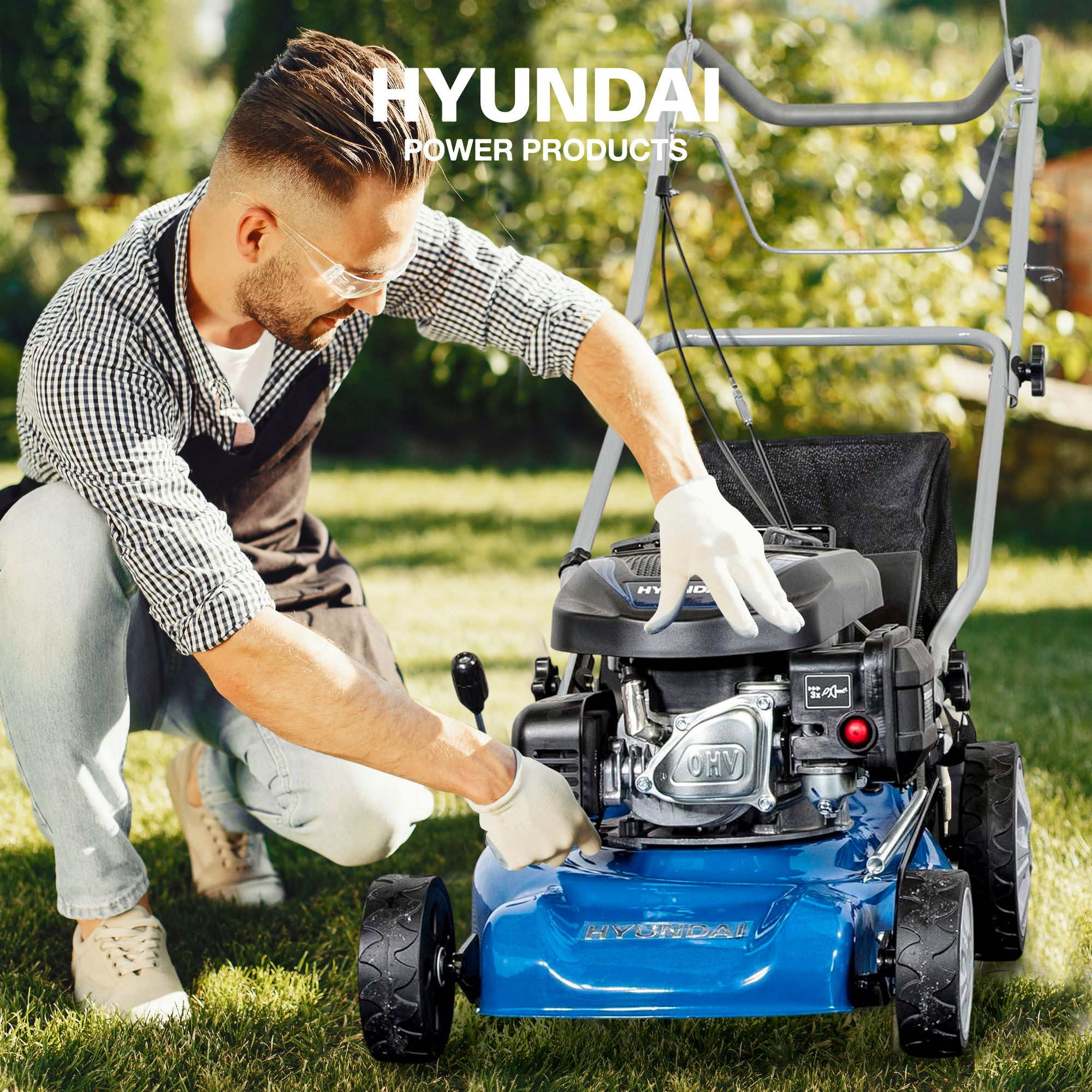 Hombre con gafas de seguridad trabaja en cortacésped Hyundai azul.