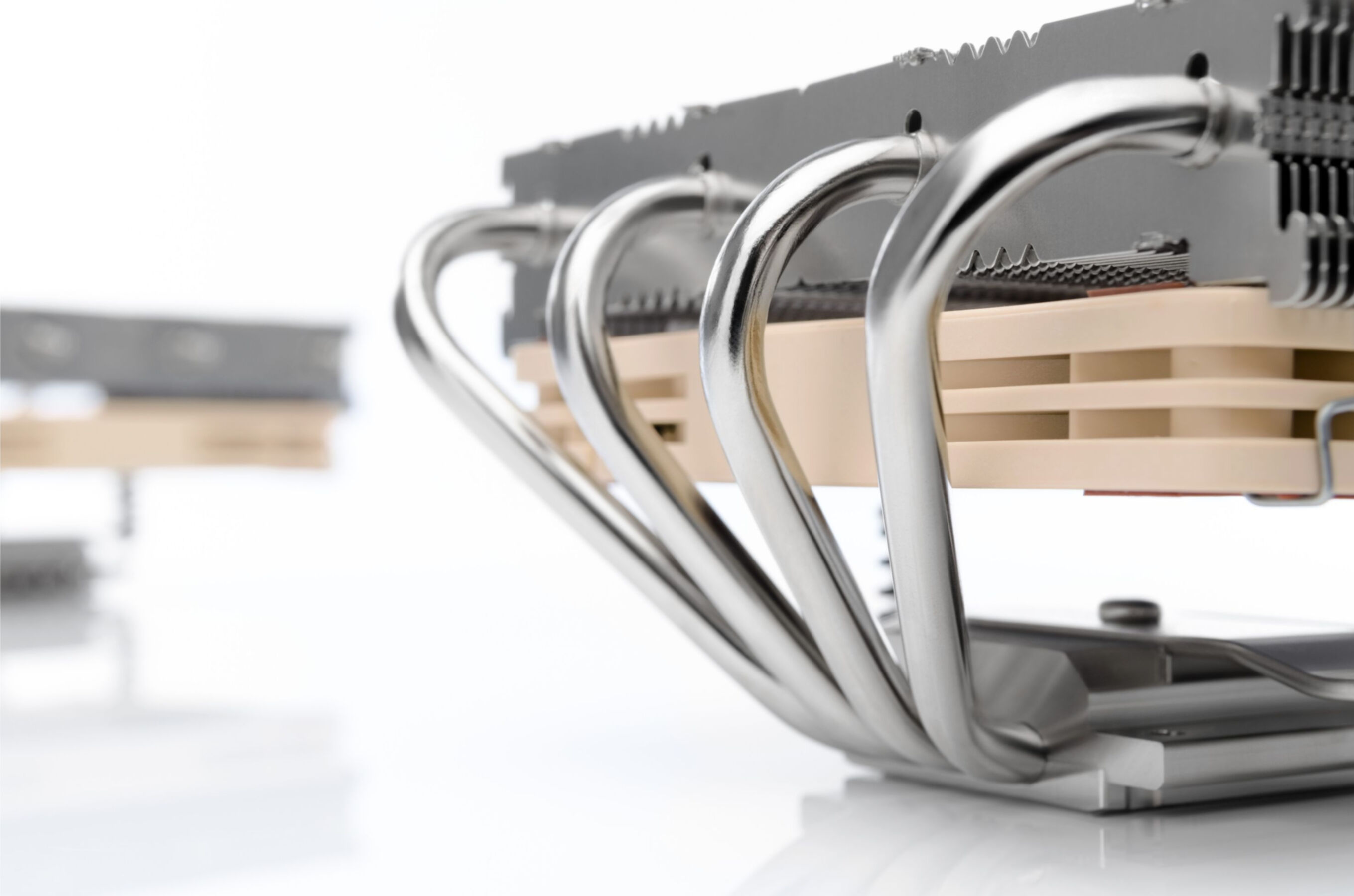 Chłodnica procesora ze srebrnymi rurkami cieplnymi i aluminiowymi żeberkami na jasnym tle.