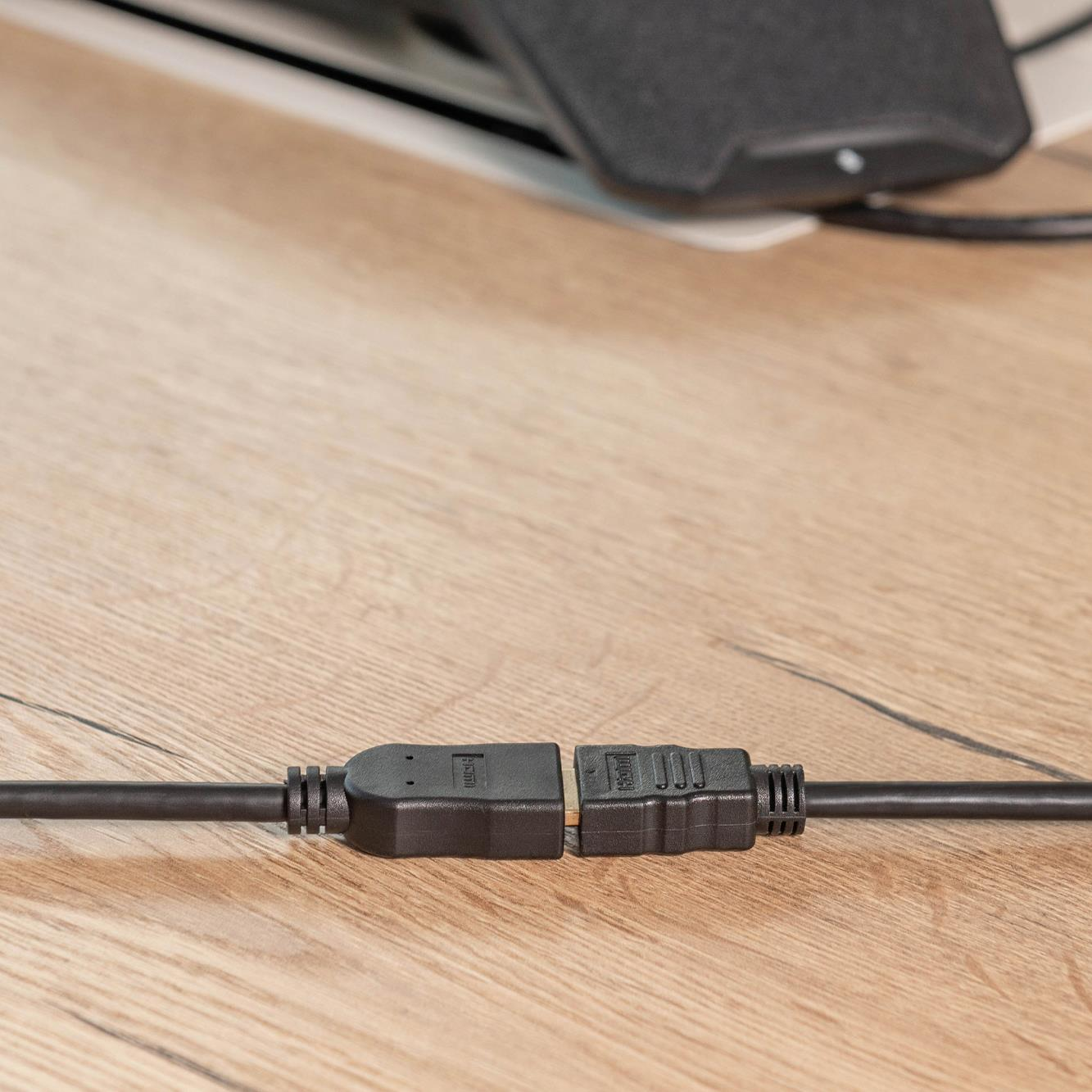 Zwei schwarze HDMI-Kabelstecker sind auf einem Holztisch verbunden.