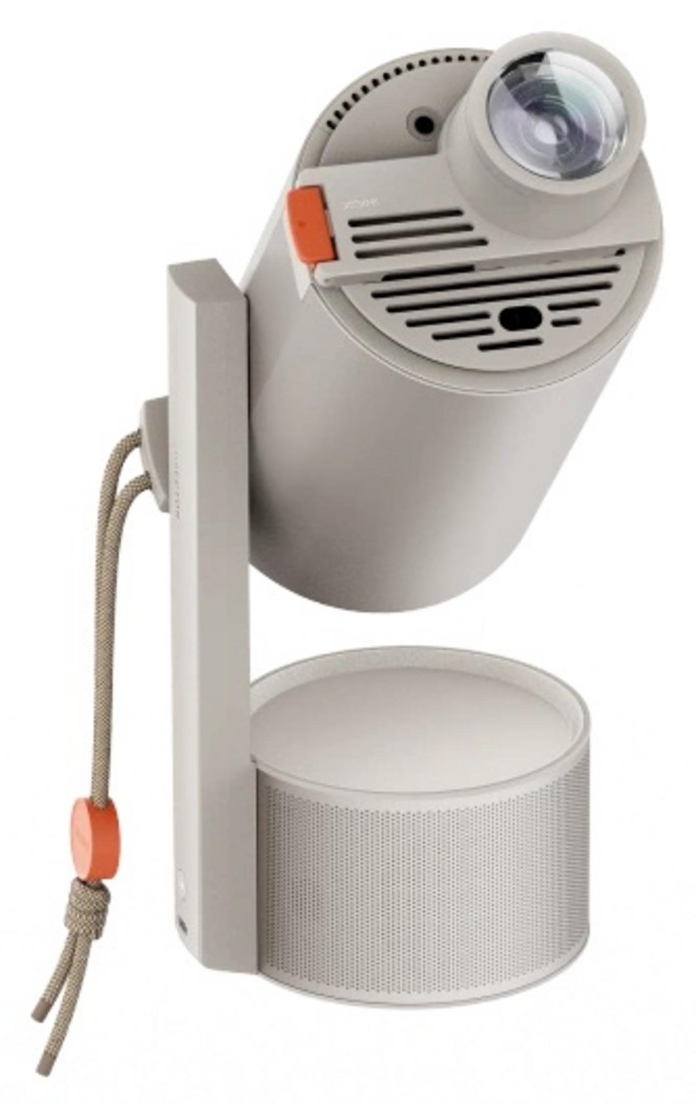 Un projecteur gris avec des accents orange et un cordon repose sur un haut-parleur.