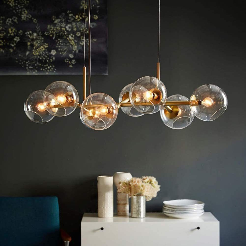 Un lampadario dorato con otto globi di vetro pende su sfondo scuro.