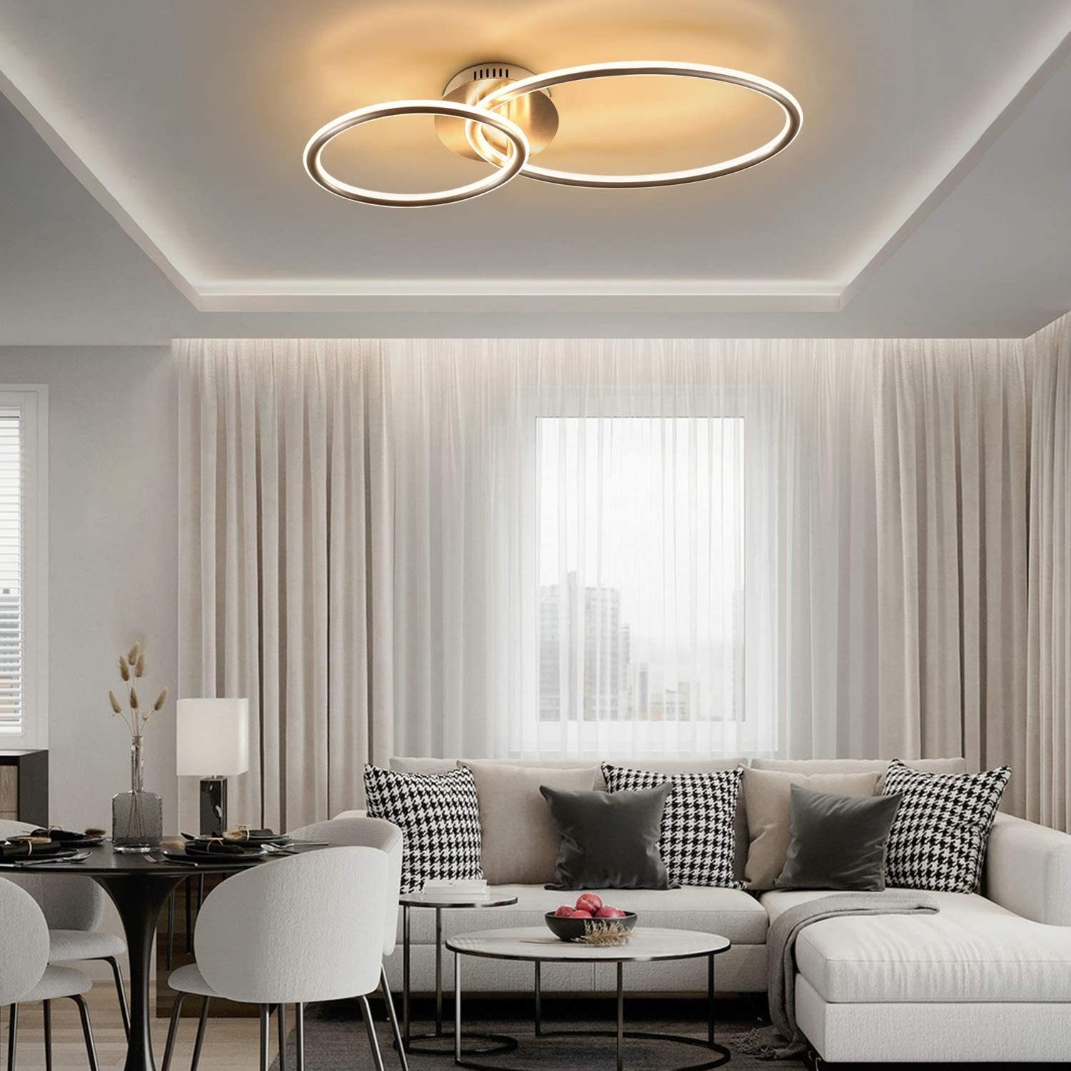 Un soggiorno moderno con divano angolare, tavolo da pranzo e lampada da soffitto.